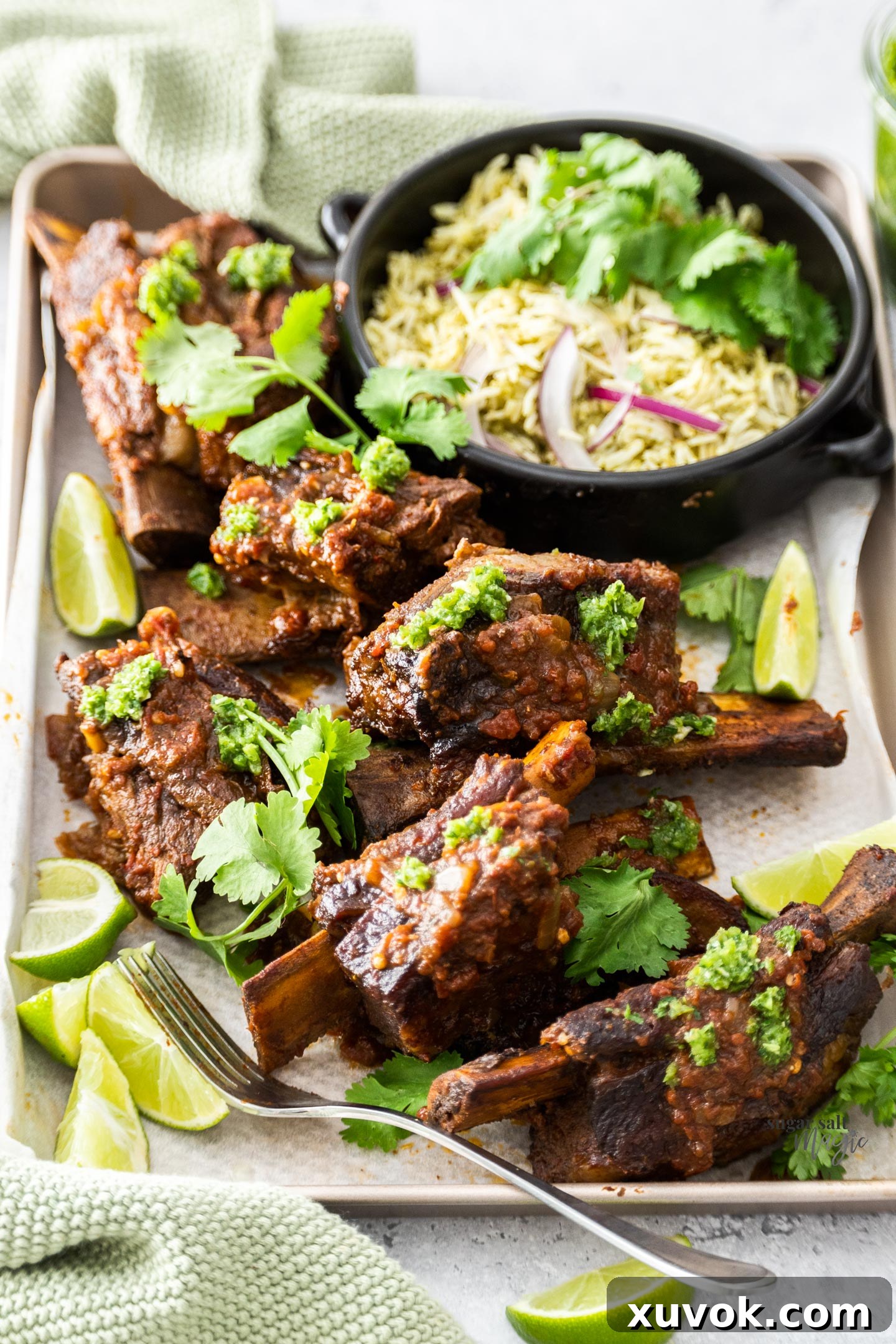 Six Mexican short ribs arranged on a serving tray with a side of rice, garnished with fresh cilantro.