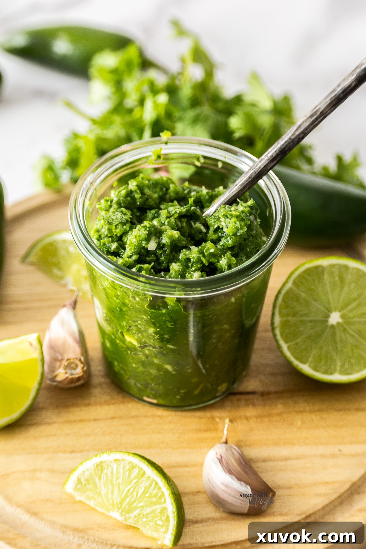 A jar filled with fresh jalapeno relish on a wooden board, showcasing its vibrant color and fresh ingredients.