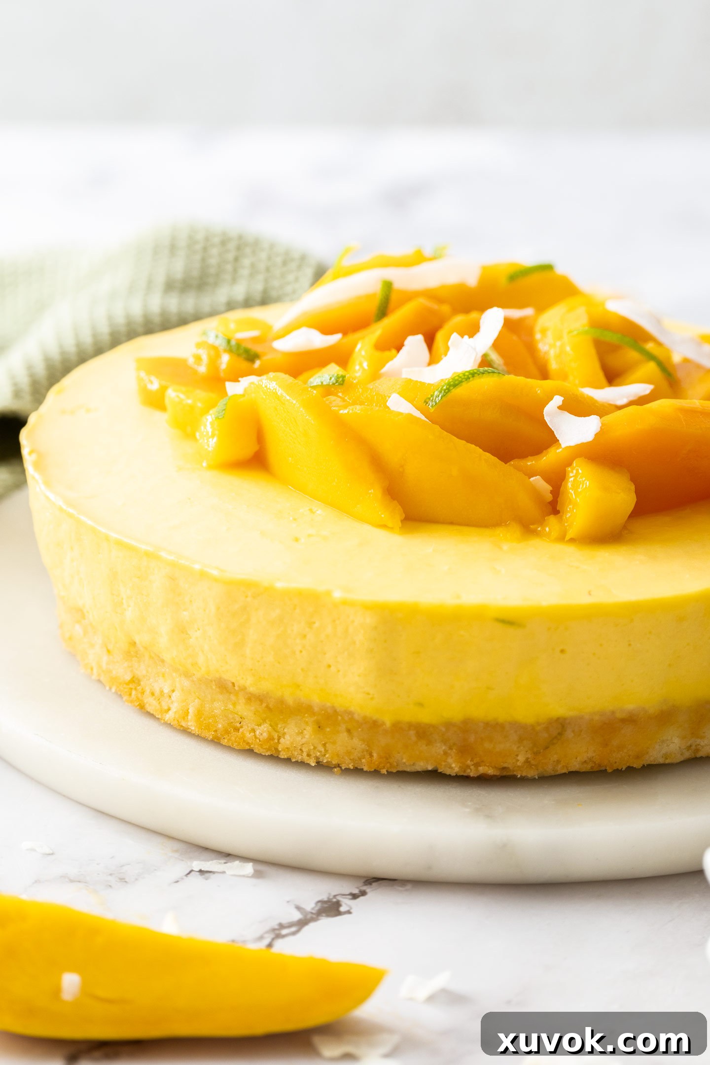A whole mango mousse cake elegantly displayed on a cake platter.