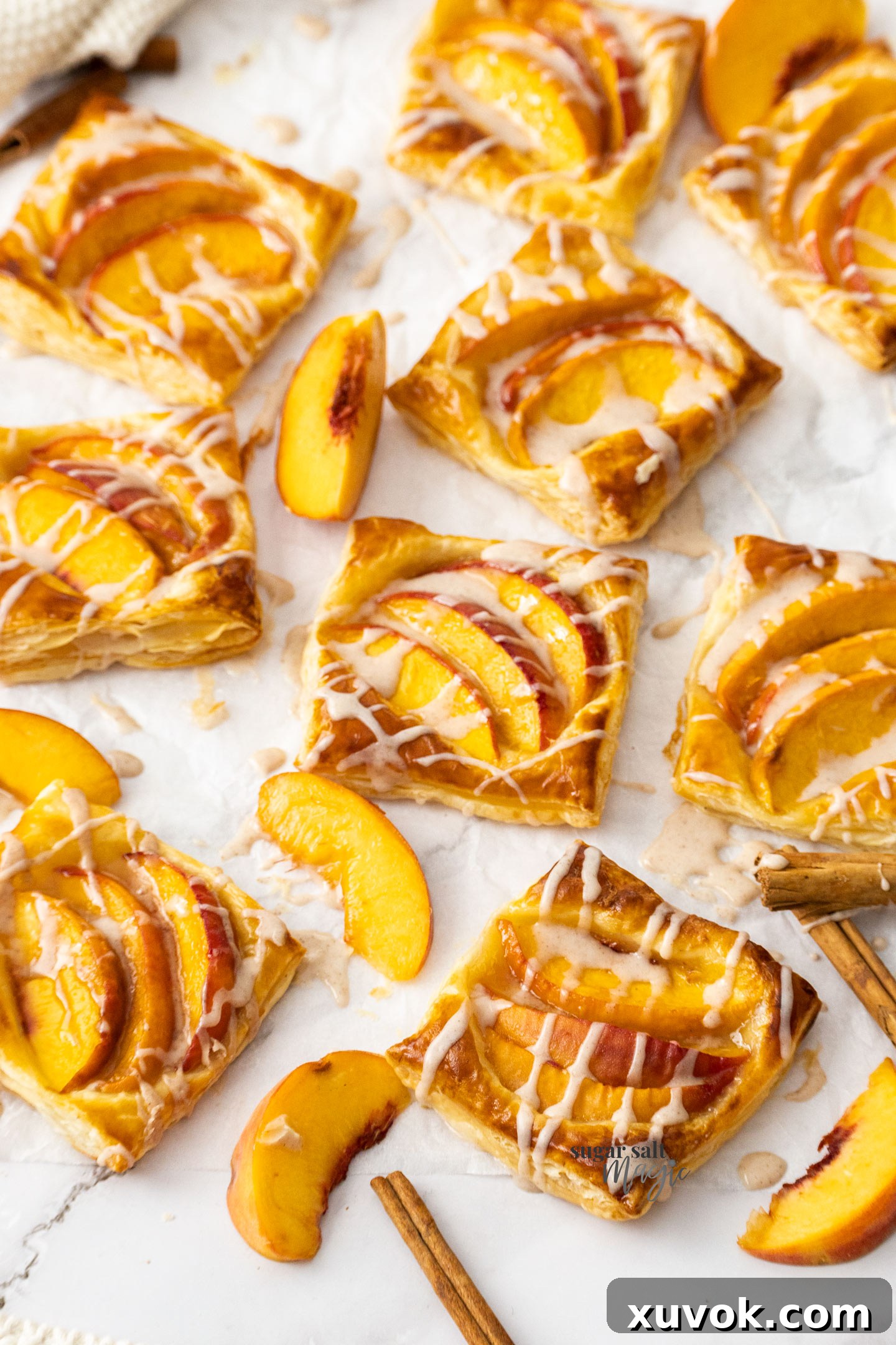 Delicate mini peach tarts adorned with a fine drizzle of icing, showcasing their golden, flaky crust and inviting fresh peach filling.