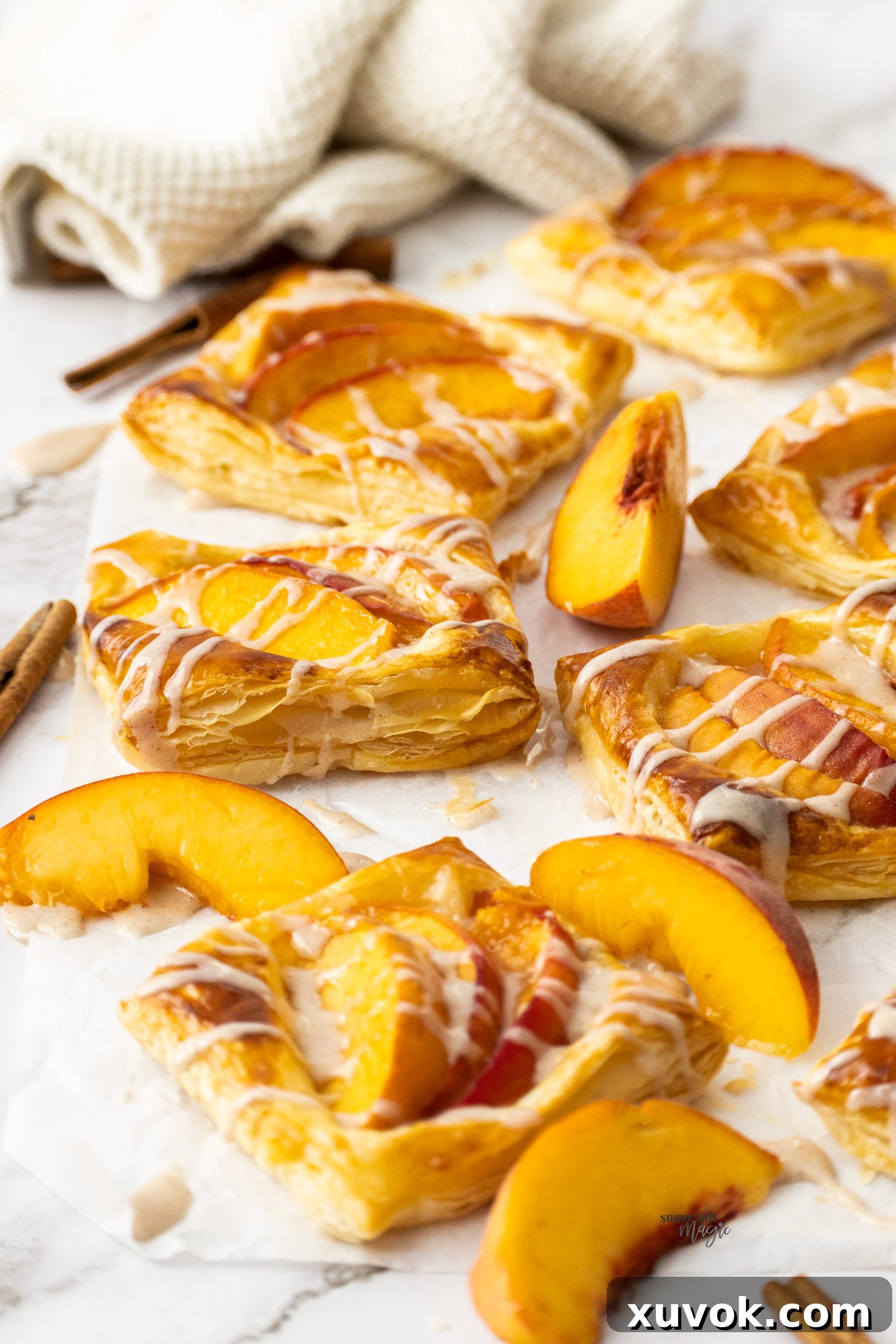 A close-up view of a baked puff pastry peach tart, revealing the distinct, golden layers of the flaky pastry and the caramelized fresh peach filling within.