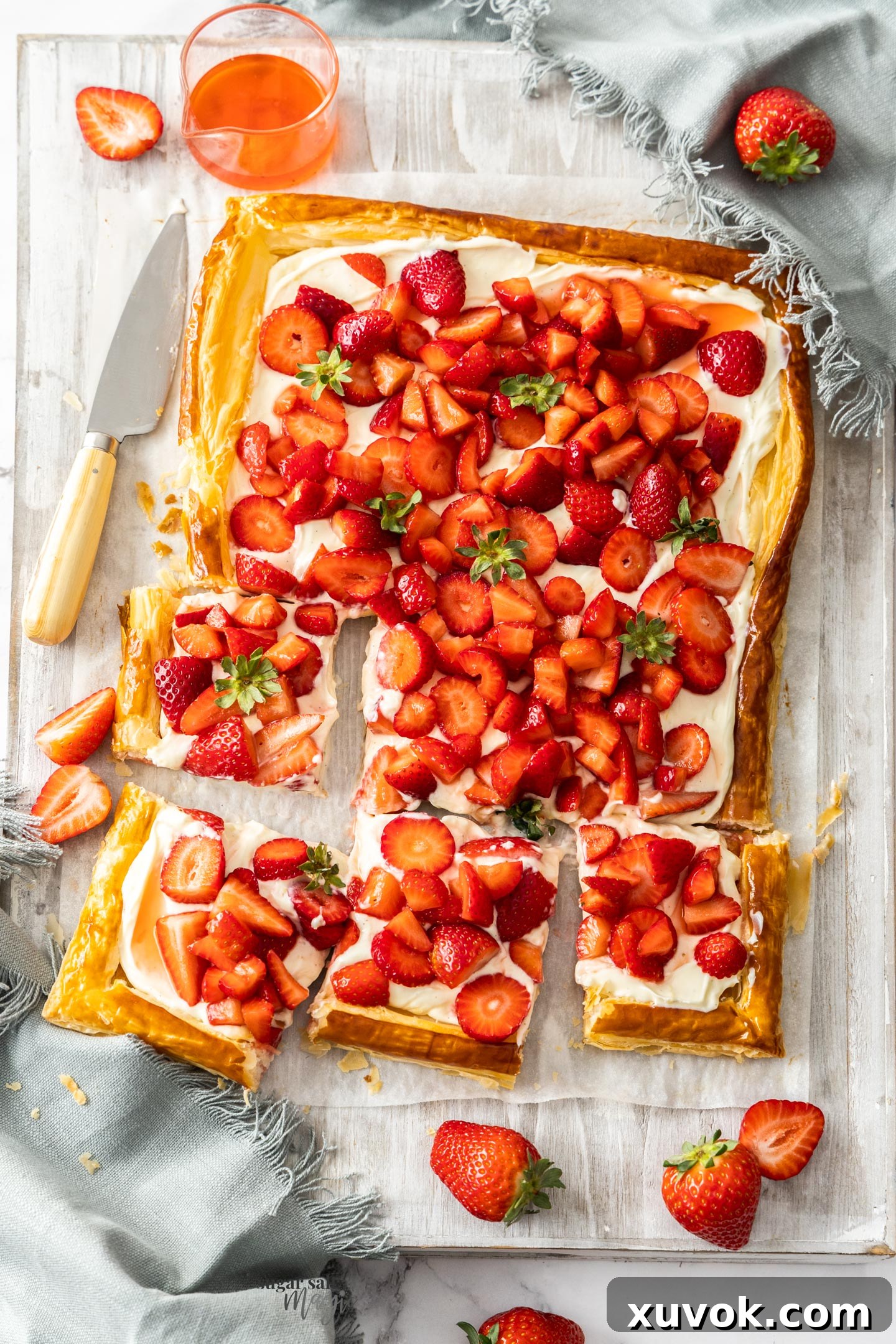 Top down view of a strawberry puff pastry tart cut into squares.