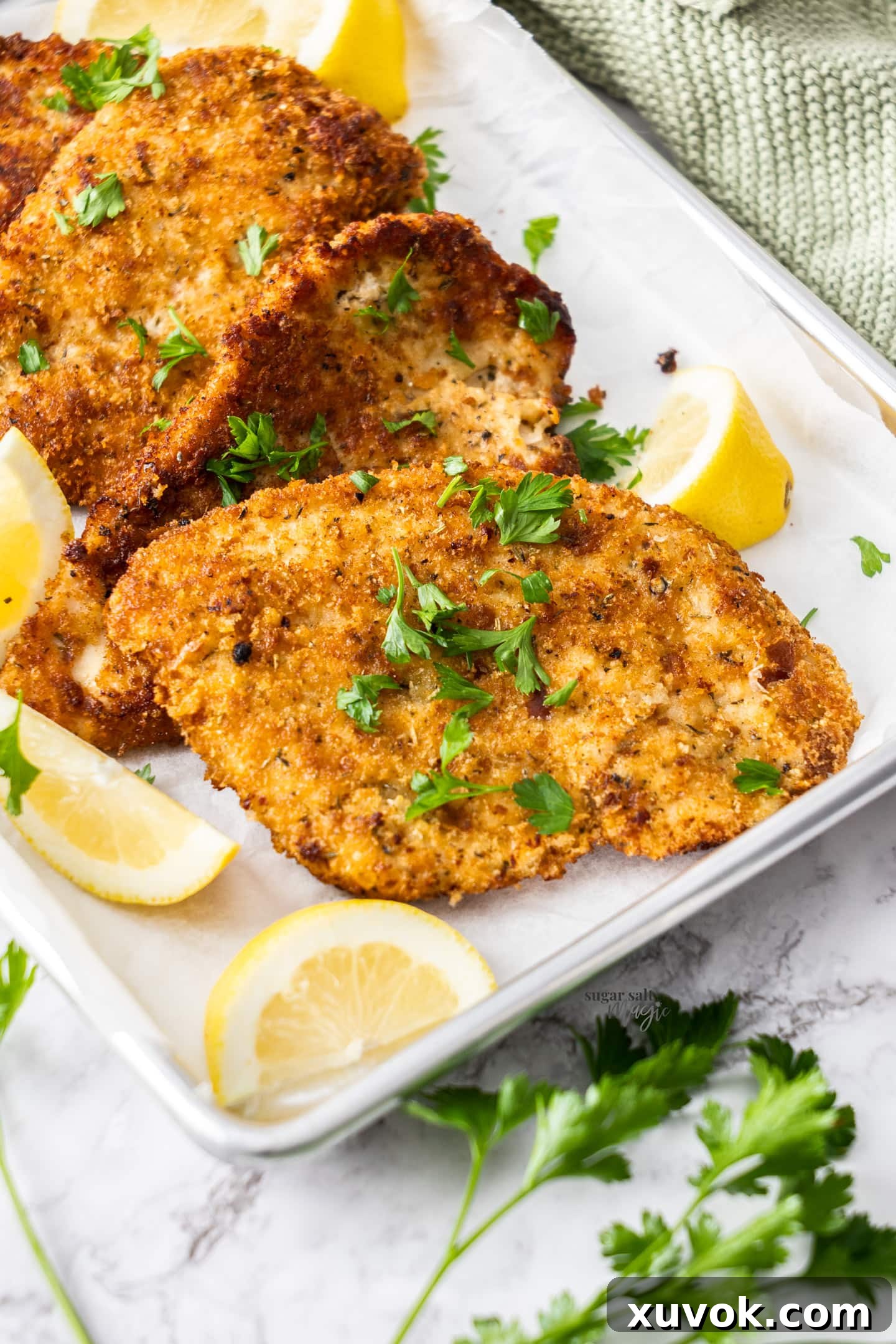 Golden brown Italian chicken cutlets, perfectly stacked on a baking tray, ready to be served.