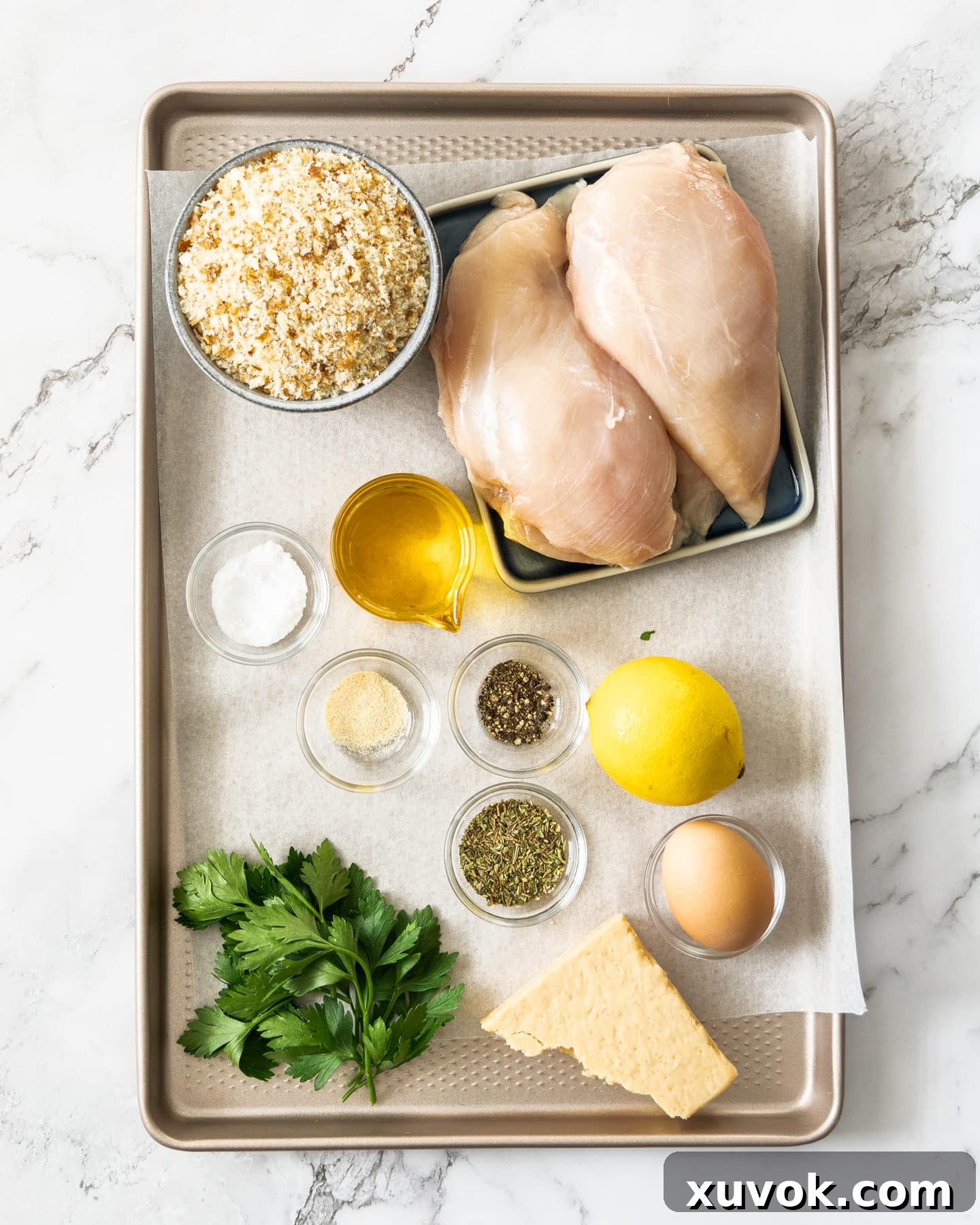 A perfectly arranged selection of fresh ingredients for Italian chicken cutlets, neatly displayed on a rustic baking tray.
