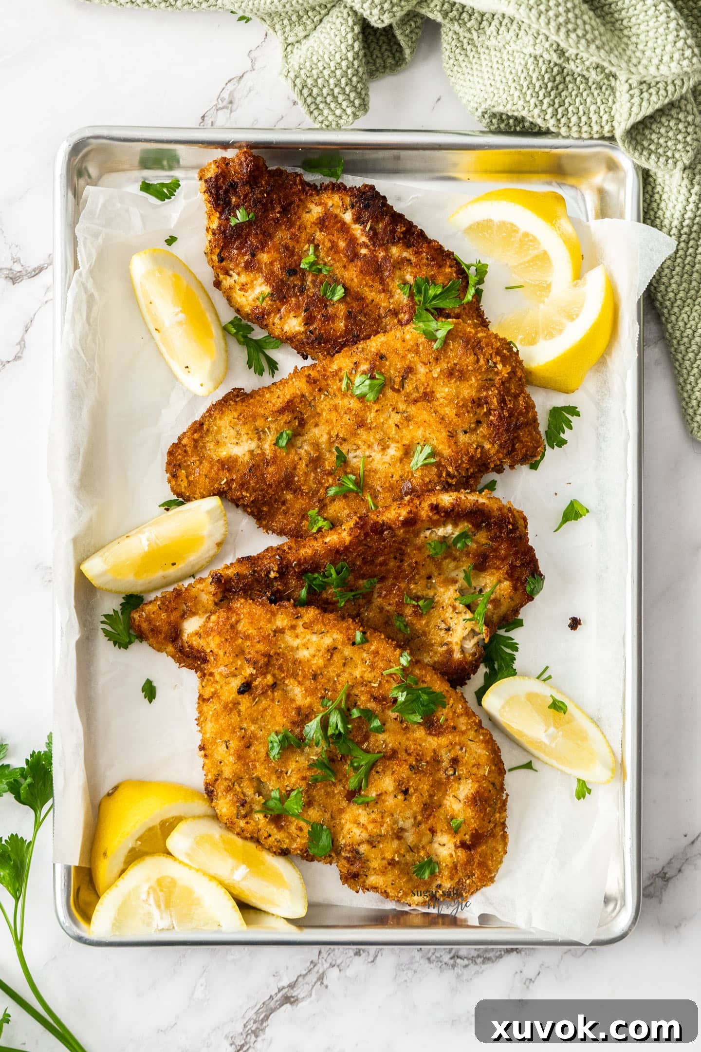 Several golden Italian chicken cutlets arranged neatly on a baking tray with a wire rack, freshly cooked and ready to be served.
