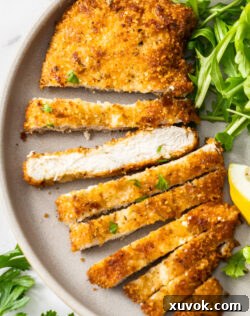 An Italian chicken cutlet sliced on a dinner plate.