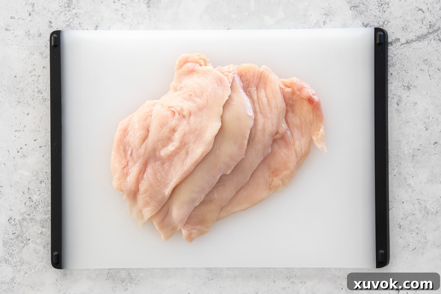 A beautifully arranged display of four uniformly flattened chicken cutlets on a wooden chopping board, ready for any culinary adventure.