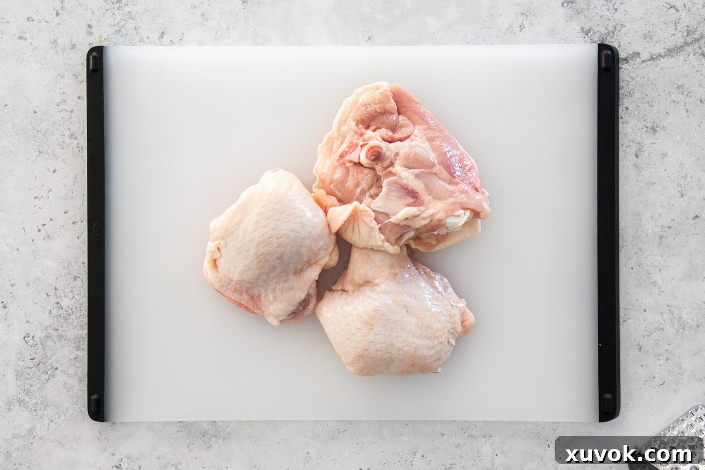 Three succulent chicken thigh cutlets, skin on, arranged invitingly on a wooden chopping board.