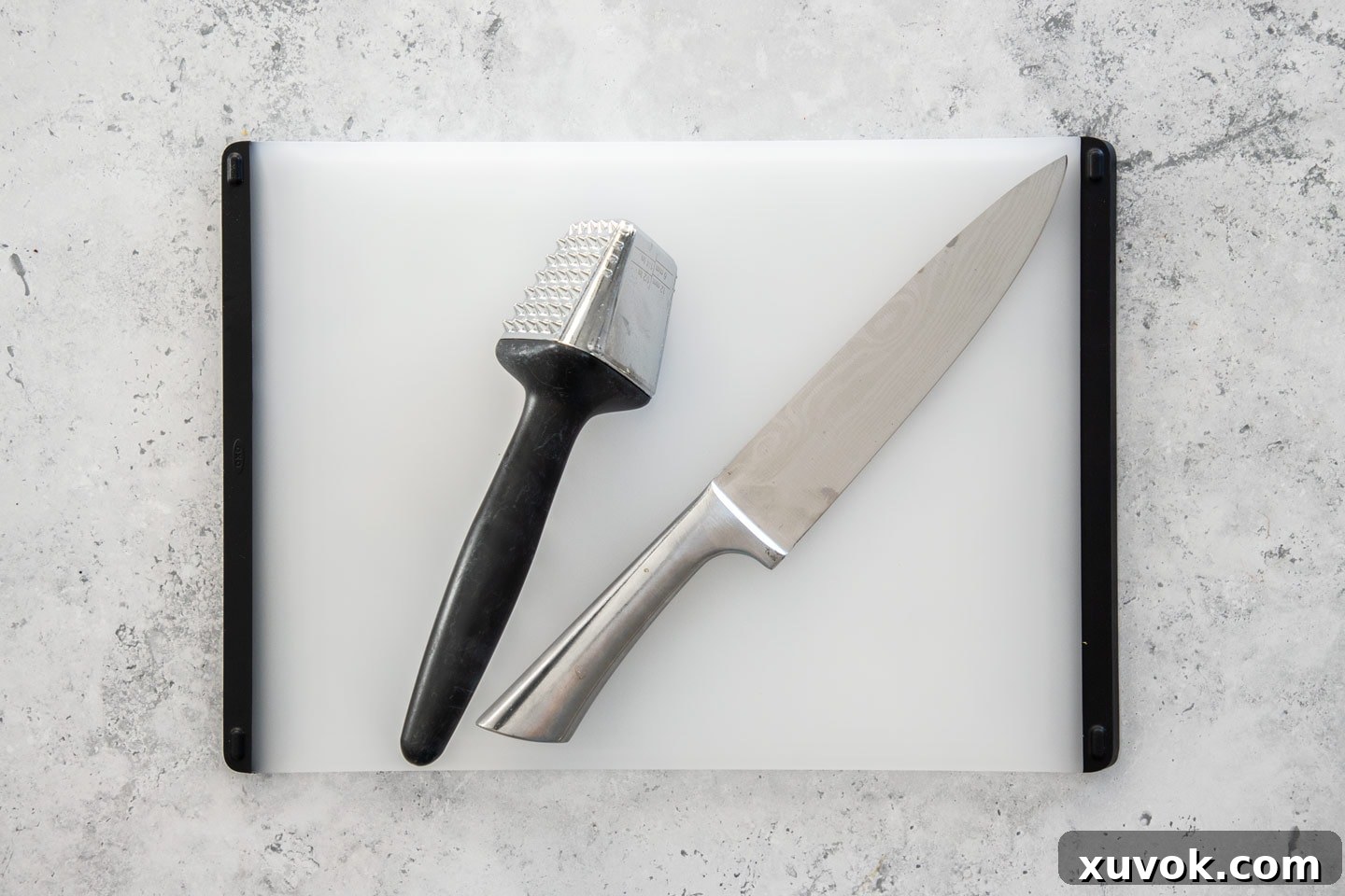 A selection of essential kitchen tools for preparing chicken: a sharp chef's knife, a sturdy meat tenderizer, and a reliable chopping board.