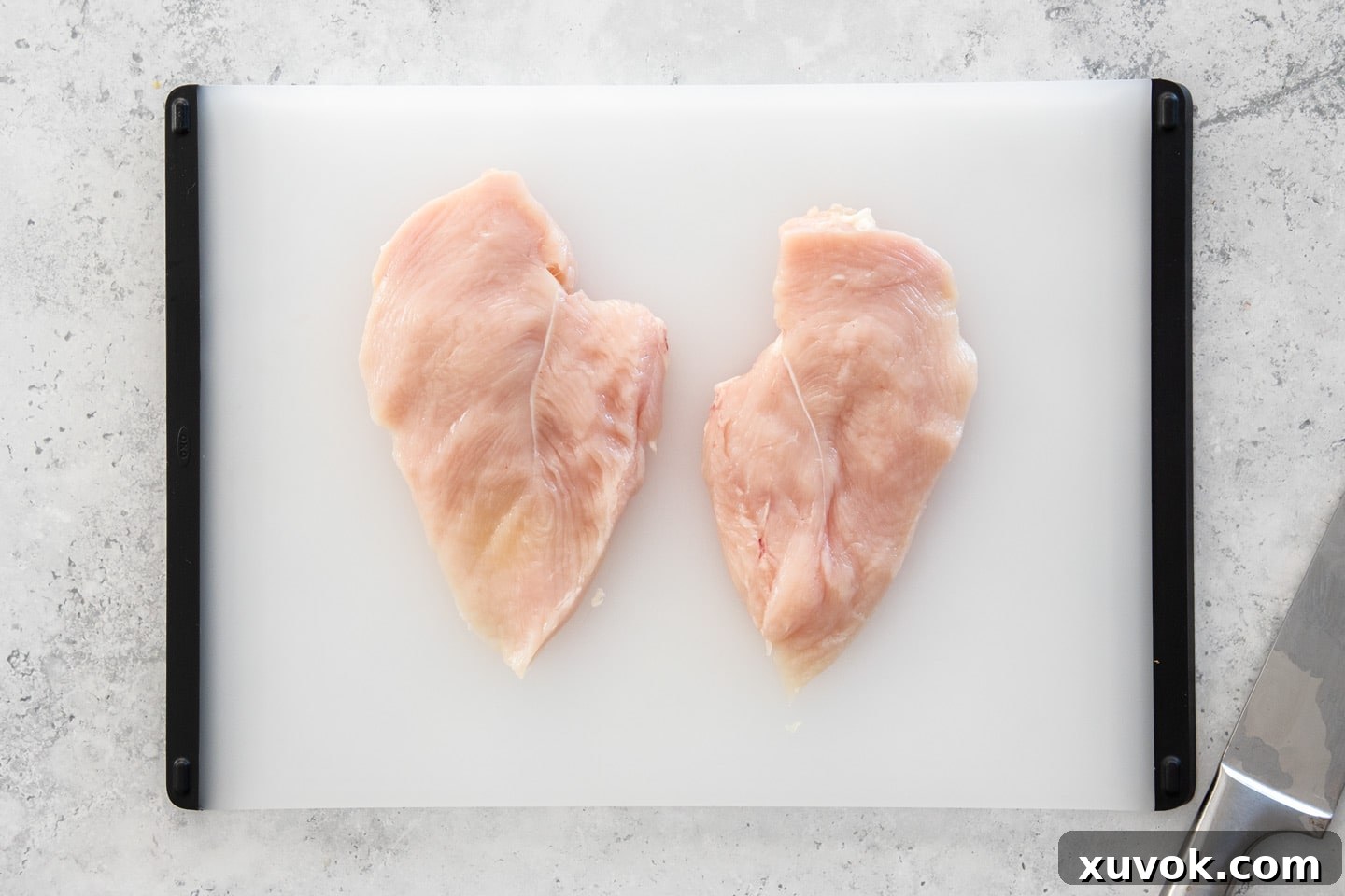 Two neatly sliced halves of a chicken breast fillet, ready to be prepared as individual cutlets.