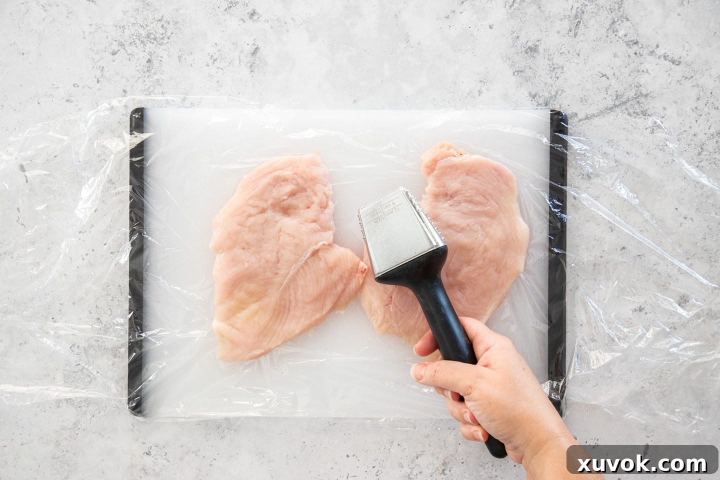 Two chicken cutlets, expertly pounded and flattened, resting on a chopping board, demonstrating their readiness for even cooking.