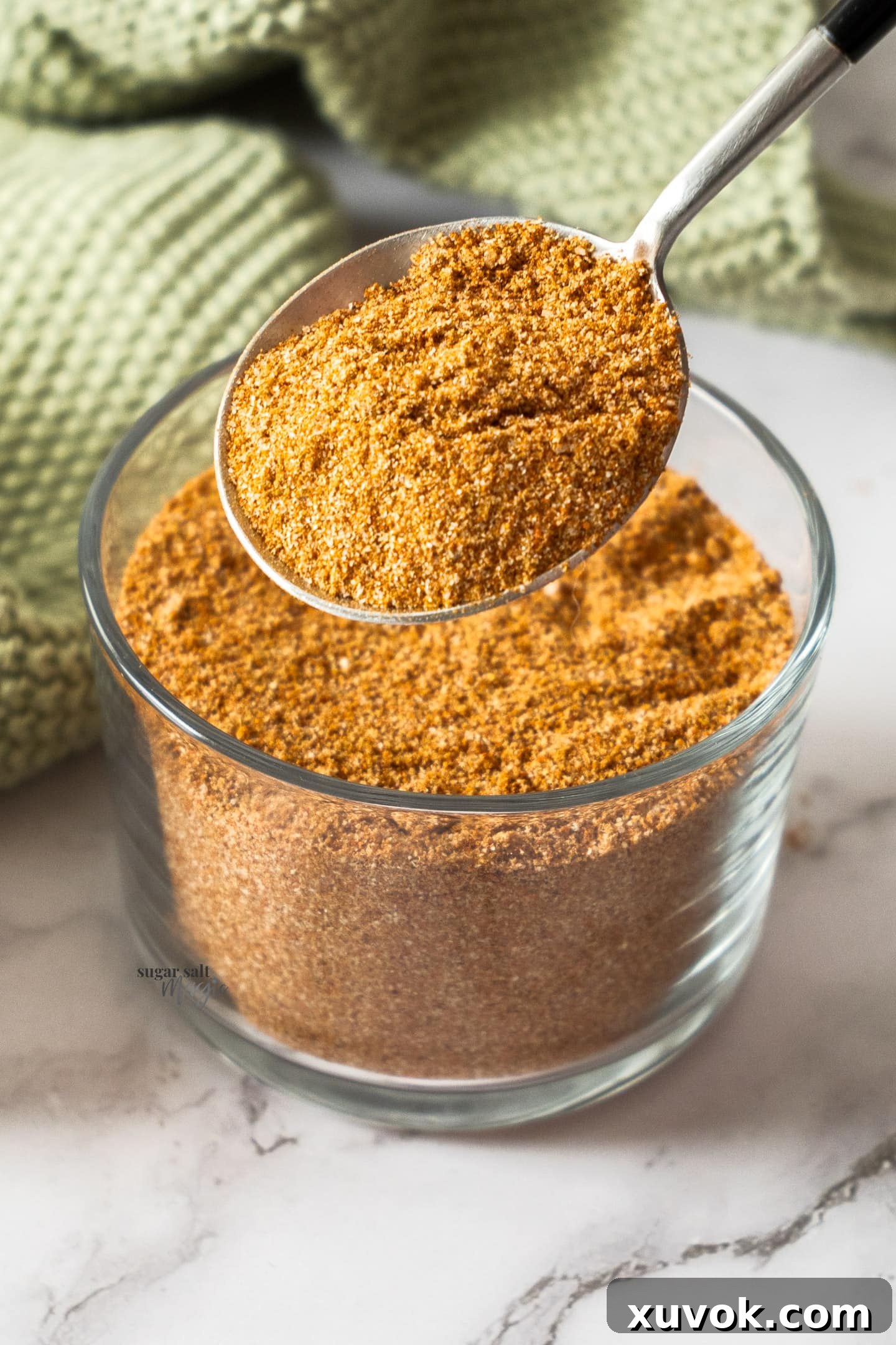 A spoon taking spice mix from a jar, showing the ease of use and the quantity of the homemade fajita seasoning.