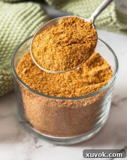 A spoon taking spice mix from a jar.