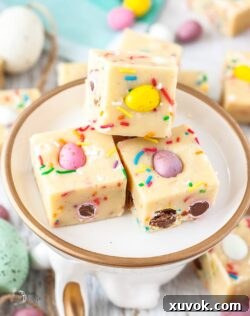 Close up of 3 squares of mini egg fudge on a plate with a gold rim.