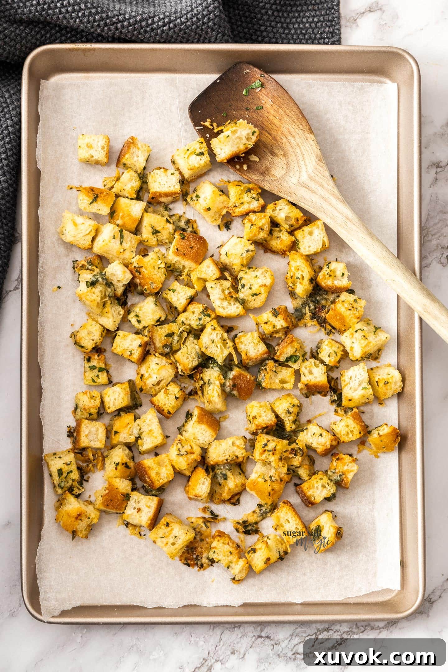 A batch of golden brown, crispy cheese and garlic croutons cooling on a baking tray.
