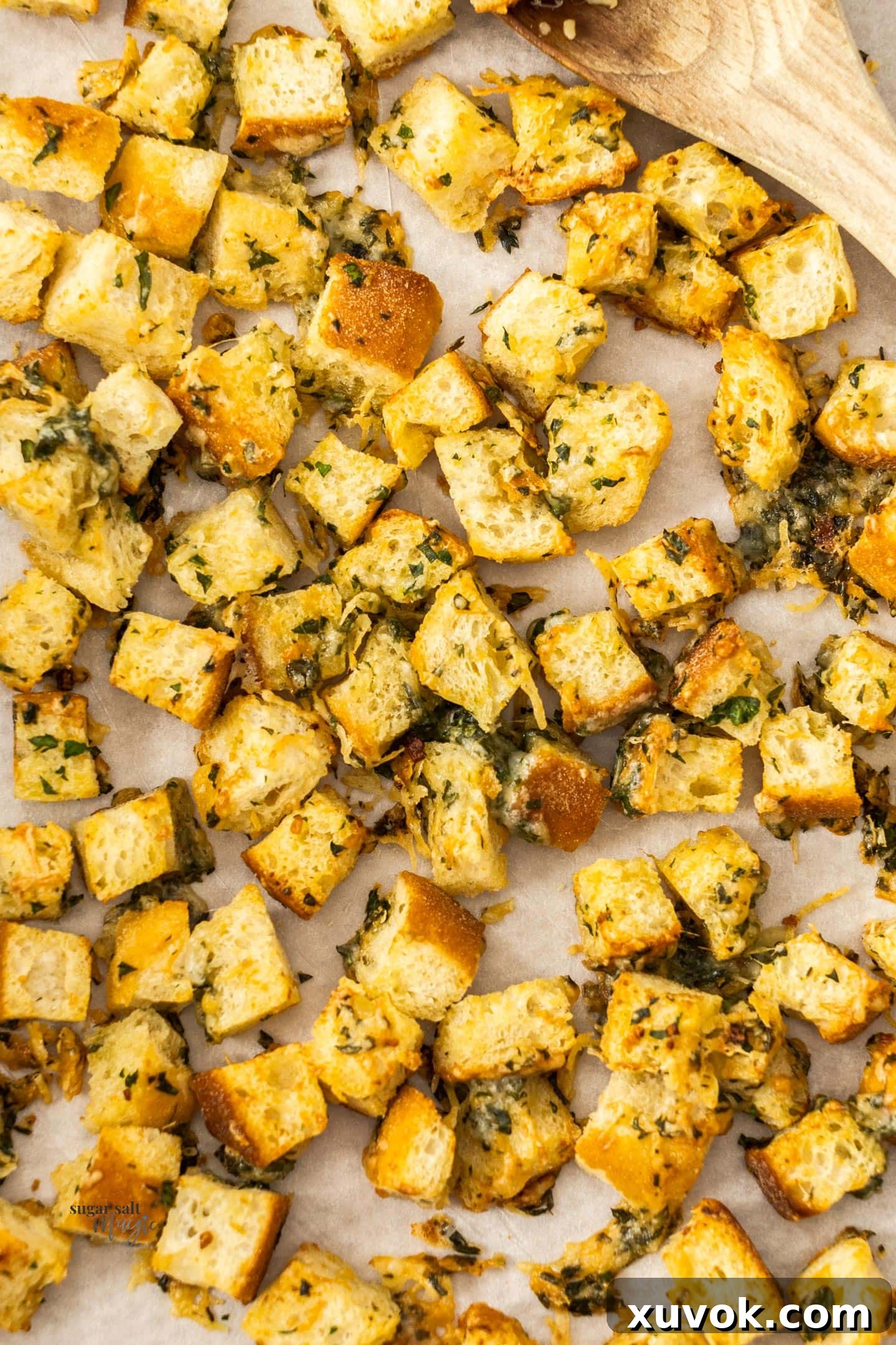 Close up of golden, crispy cheese garlic croutons piled on a baking tray, ready to eat.