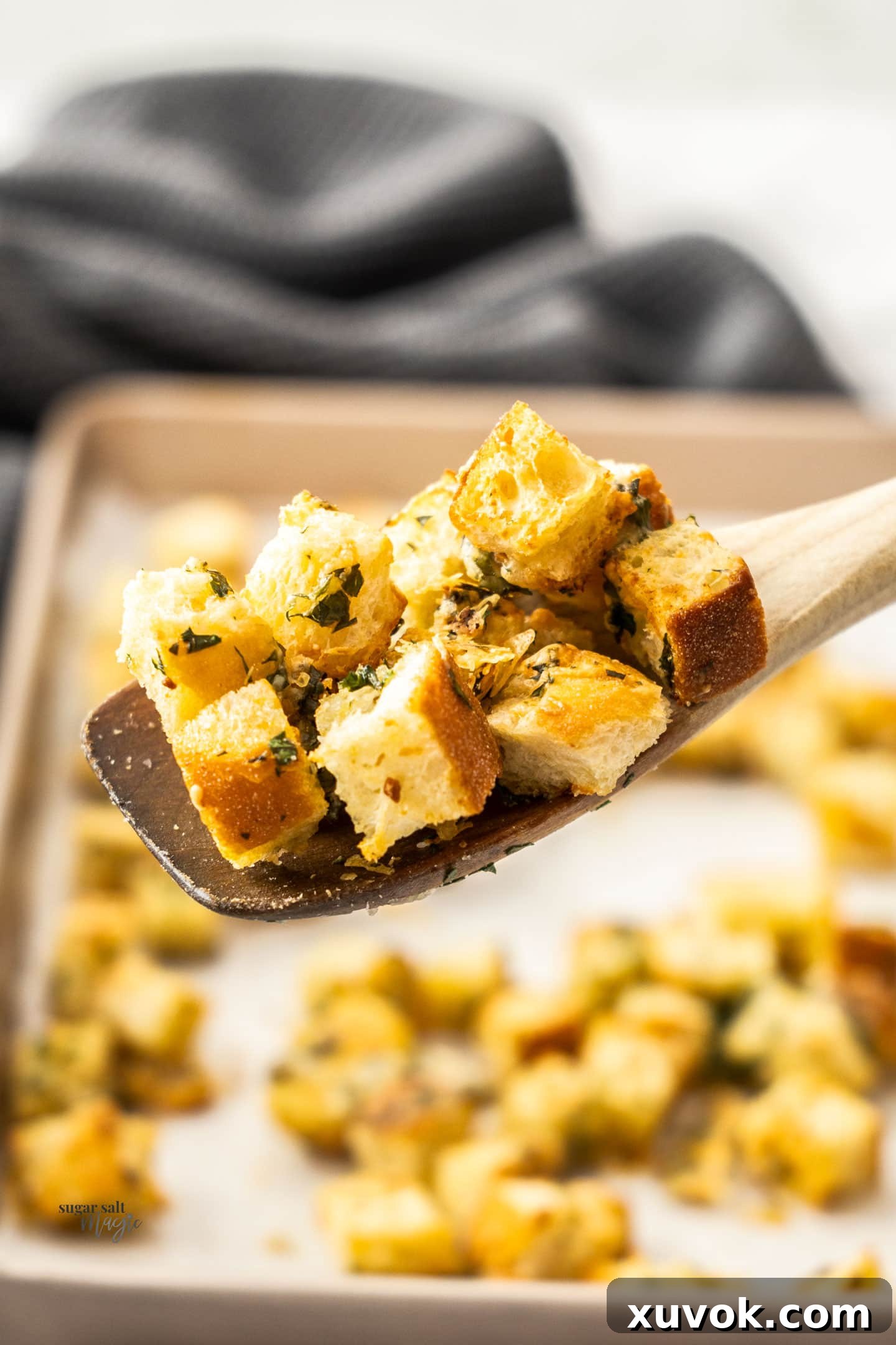 Scoop of cheese garlic croutons on a wooden spoon, ready to be served.