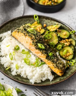 A dish filled with rice, furikake salmon, and cucumber salad, ready to be enjoyed.