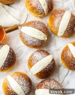 A top-down view of nine perfectly arranged Maritozzi buns, generously filled with cream and dusted with icing sugar, showcasing their elegant presentation and tempting appeal.
