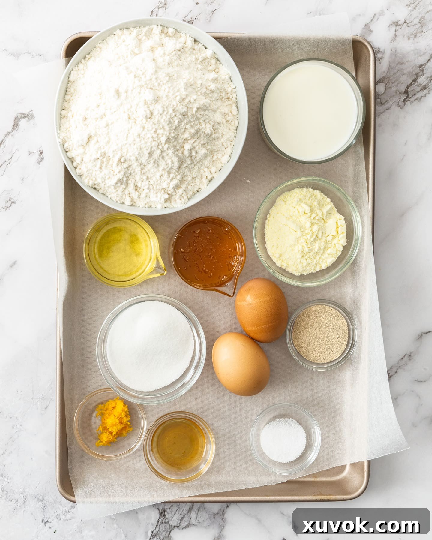 A flat lay photograph showcasing all the dry and wet ingredients for making Maritozzi dough, neatly arranged on a baking tray, ready for mixing. It visually represents the recipe's components before preparation.
