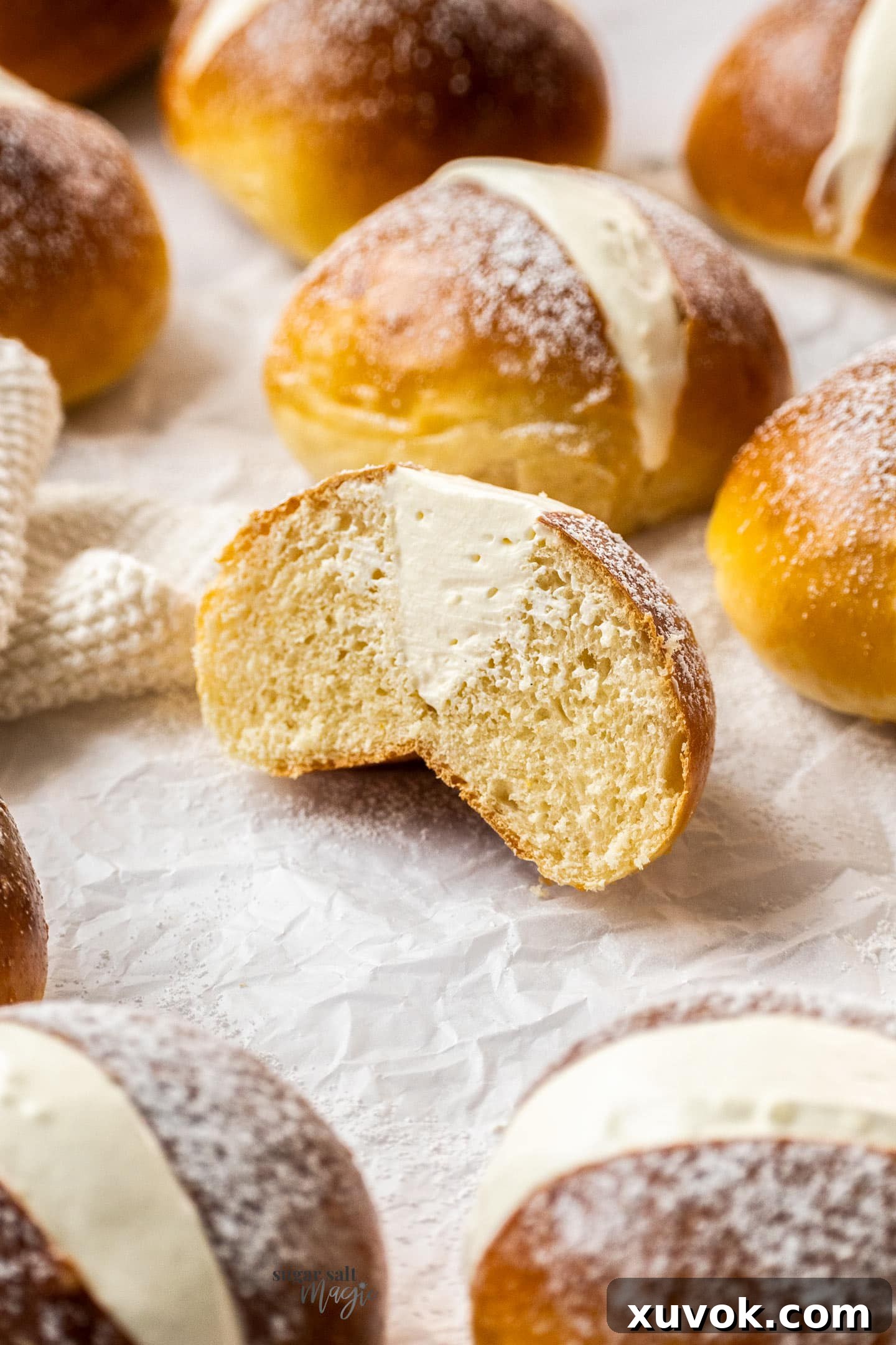 A single maritozzo bun, expertly cut in half, reveals its soft, airy crumb and the generous, fluffy vanilla whipped cream filling, illustrating the perfect cross-section of this Roman pastry.