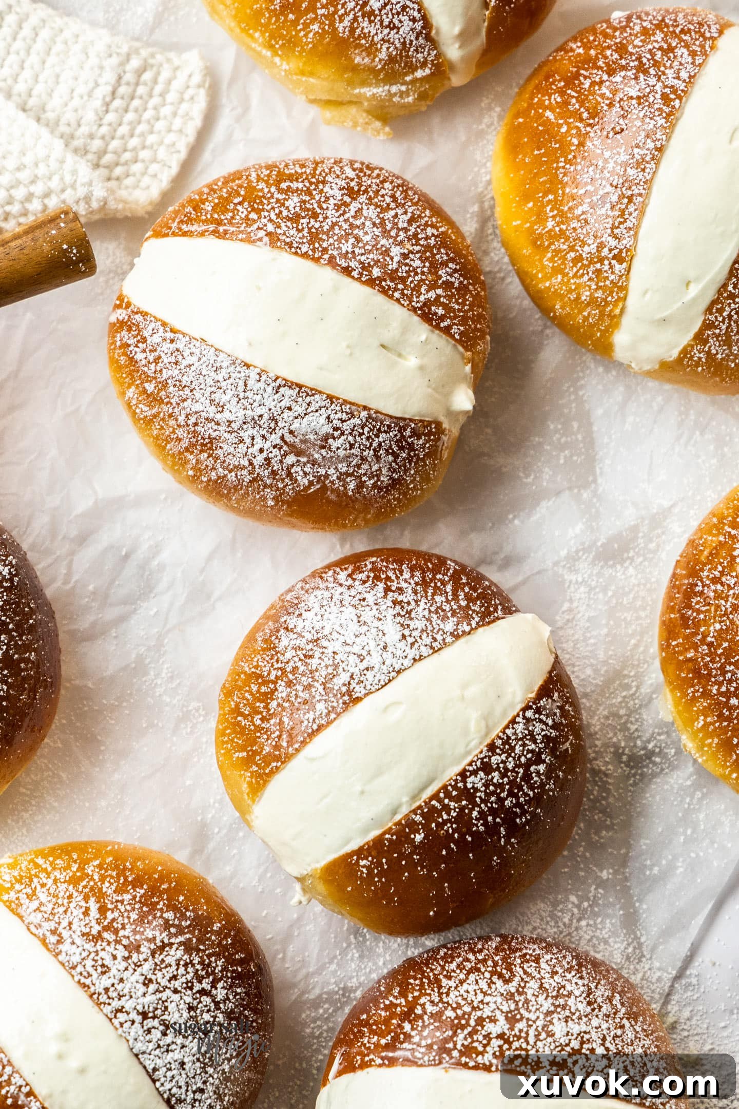 A top-down view of eight perfectly arranged Maritozzi buns, generously filled with cream and dusted with icing sugar, showcasing their elegant presentation and tempting appeal.