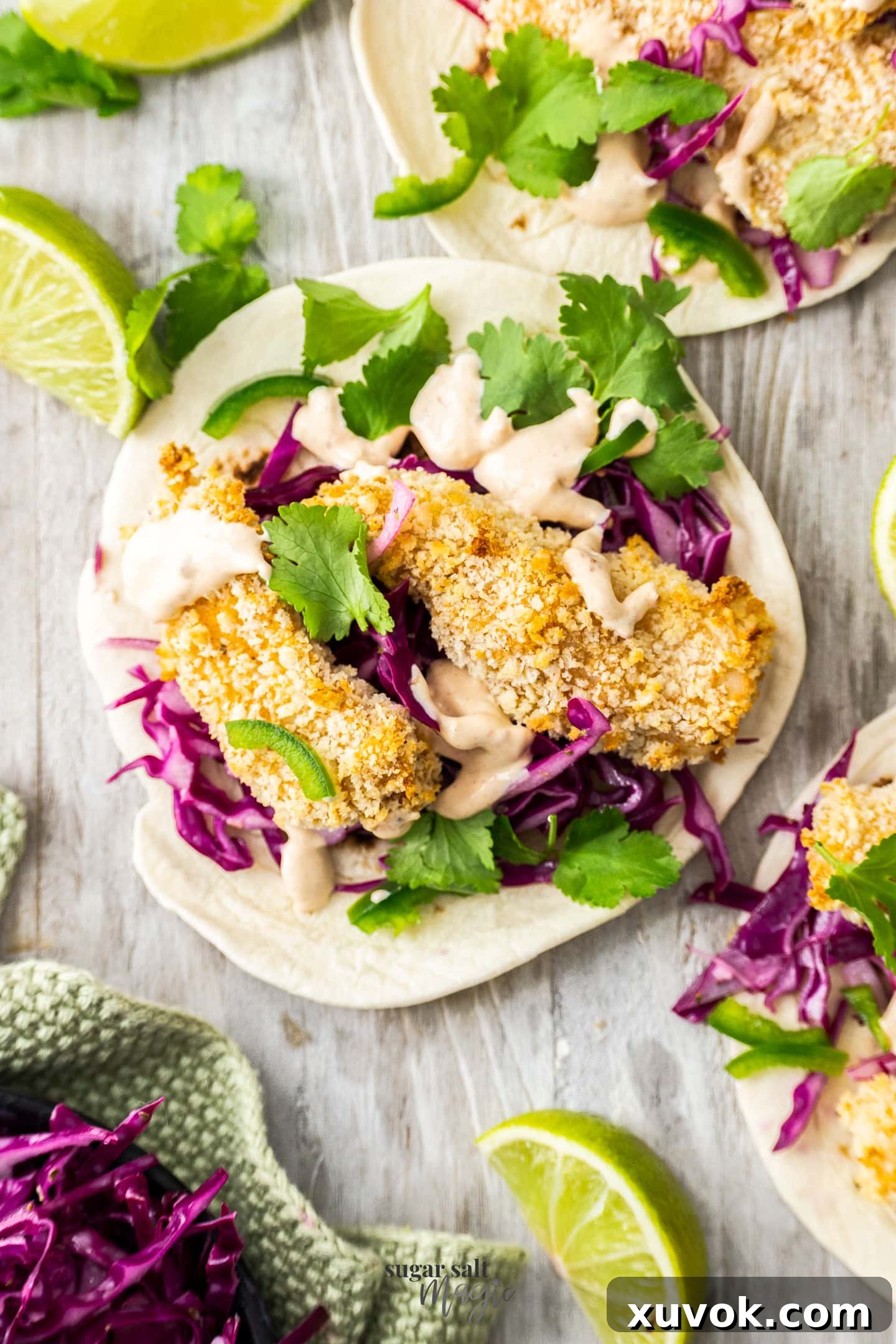 Two pieces of fish on a tortilla with cabbage and coriander.