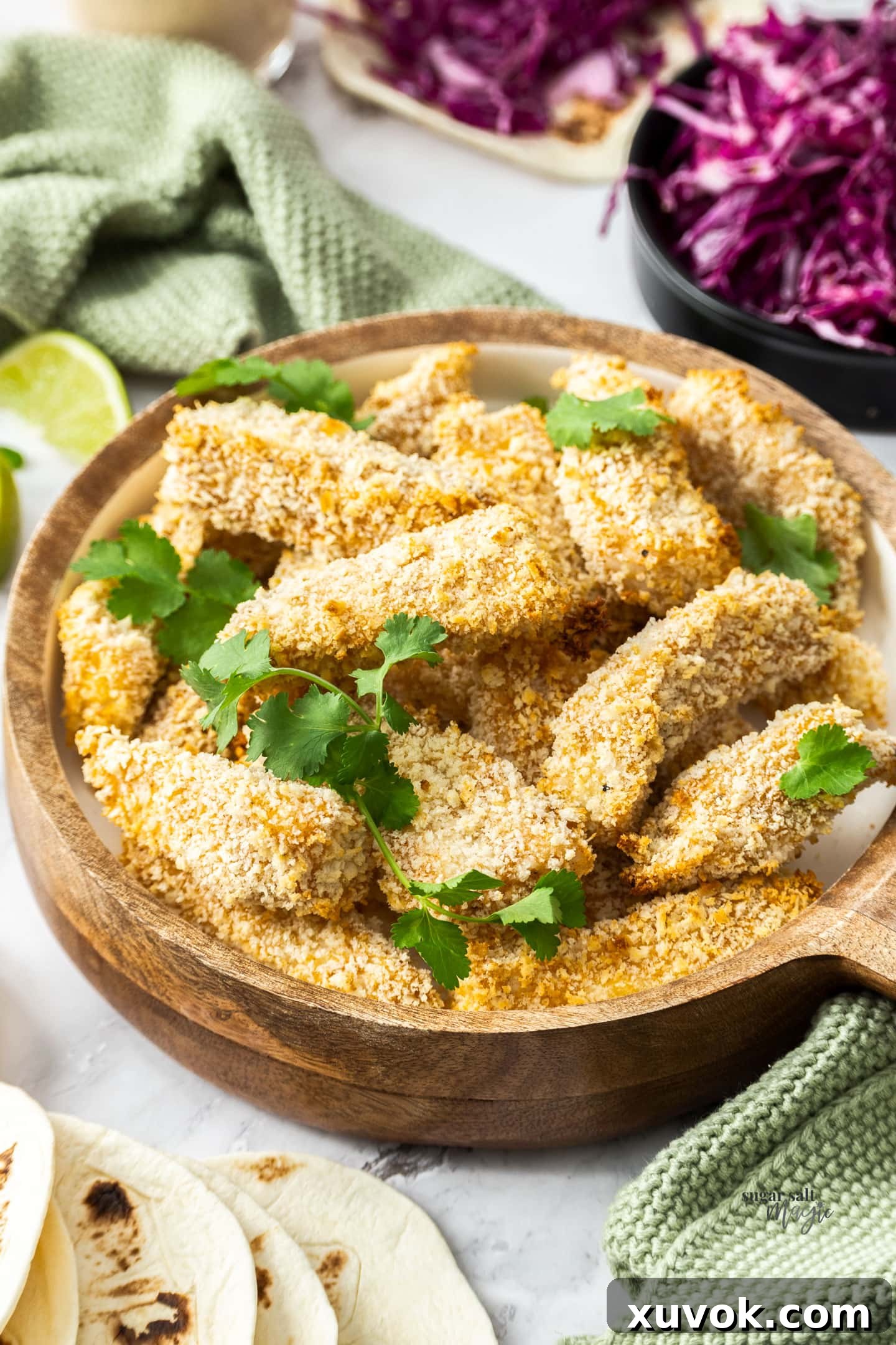 Pieces of baked crumbed fish in a wooden bowl.