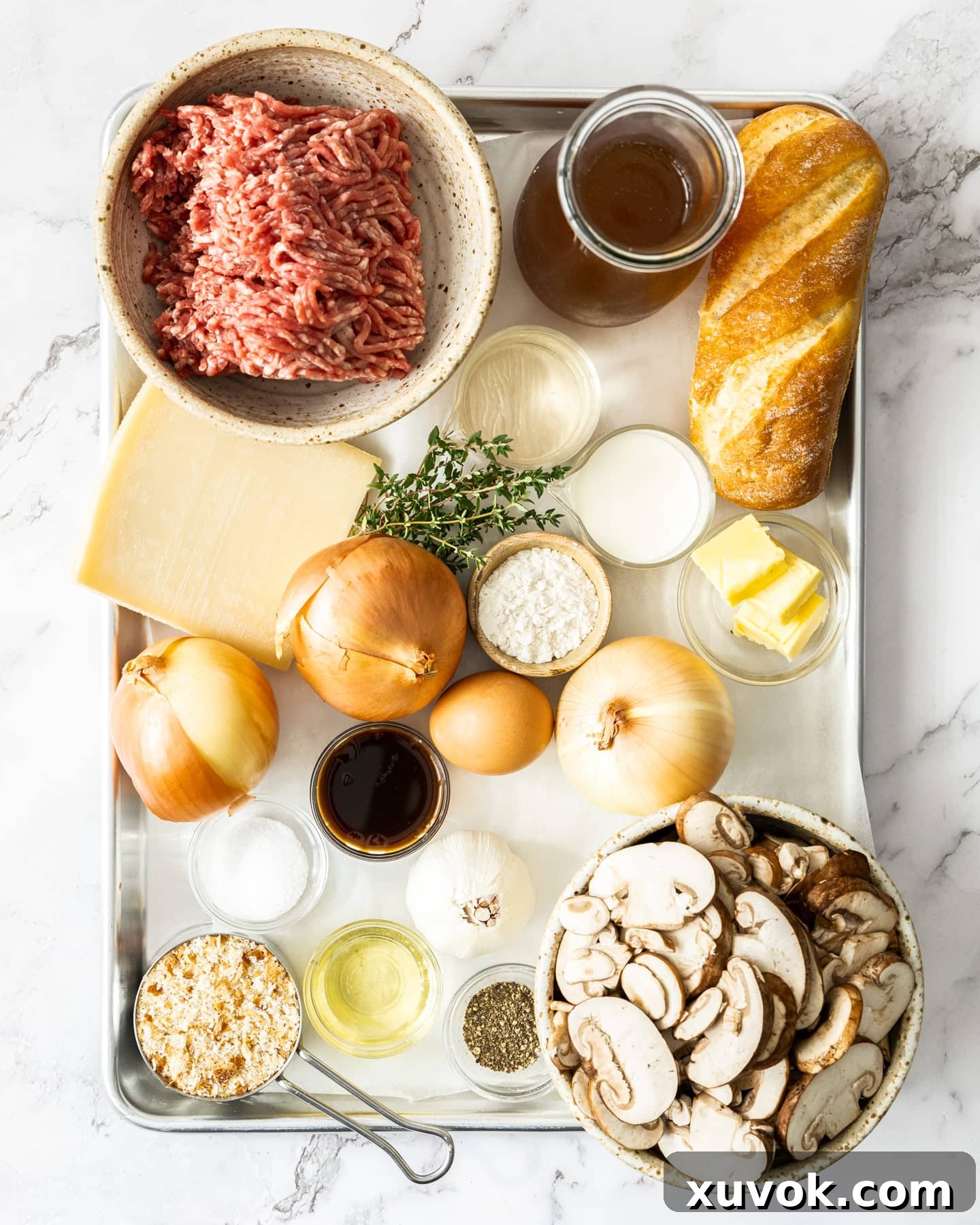 Ingredients for French onion meatballs laid out on a baking tray, showcasing fresh produce, meat, and cheese.