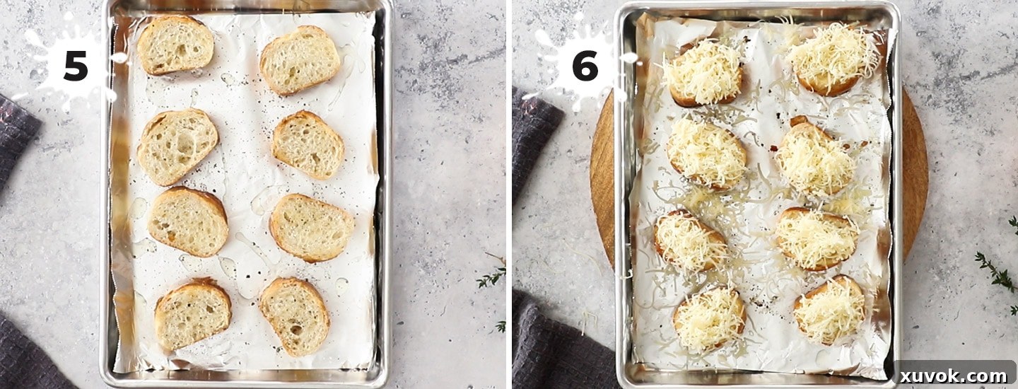 Golden-brown baguette slices topped with shredded Gruyere cheese on a baking tray, ready for melting under the broiler.