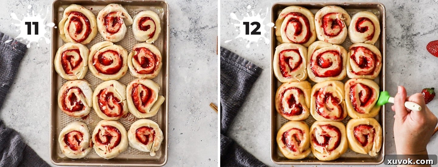 A rectangular baking pan filled with unbaked strawberry cinnamon rolls, perfectly spaced for their second rise.