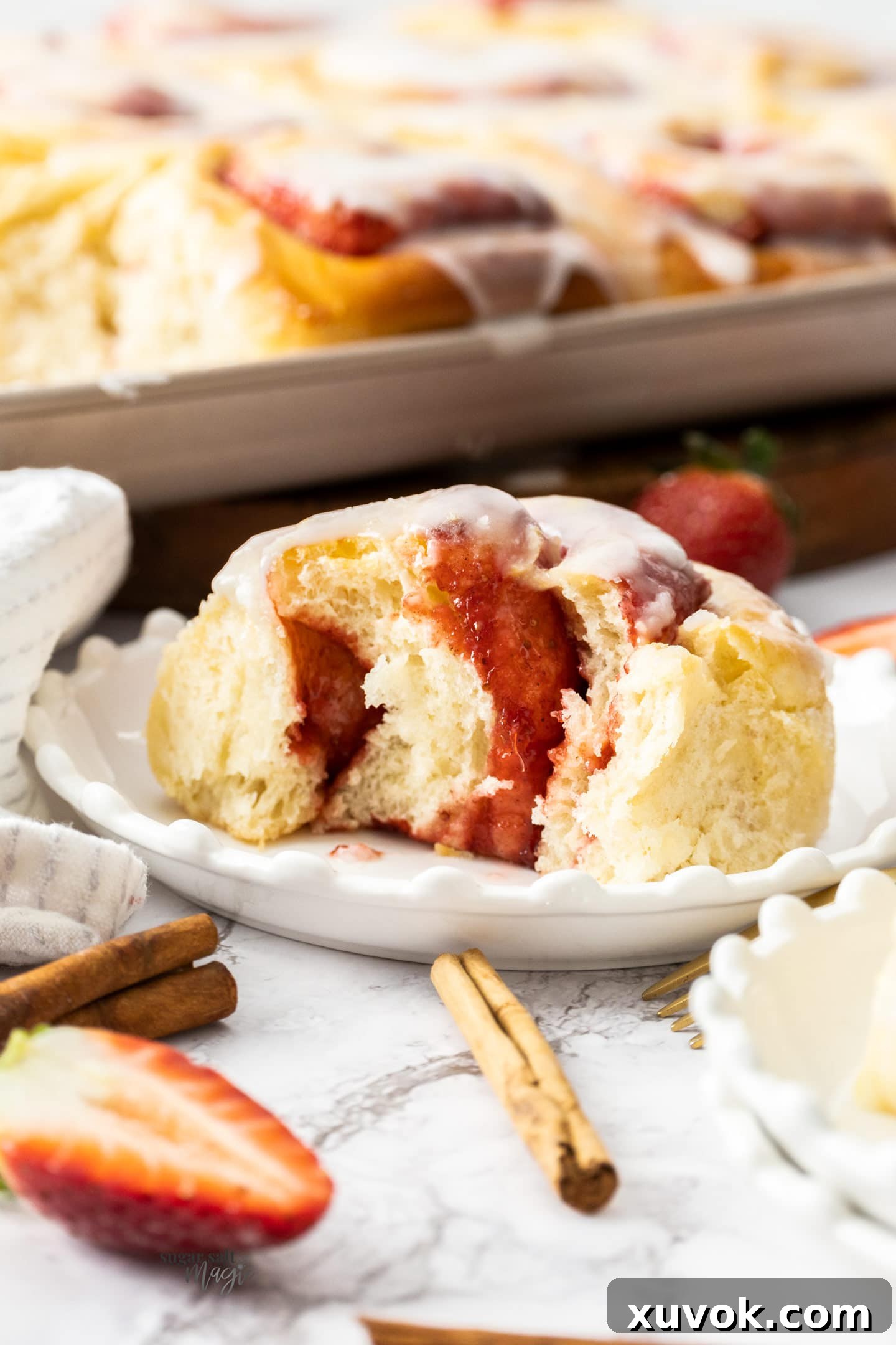 A close-up shot of a strawberry cinnamon roll torn open, revealing its soft, swirled interior and the luscious strawberry filling.