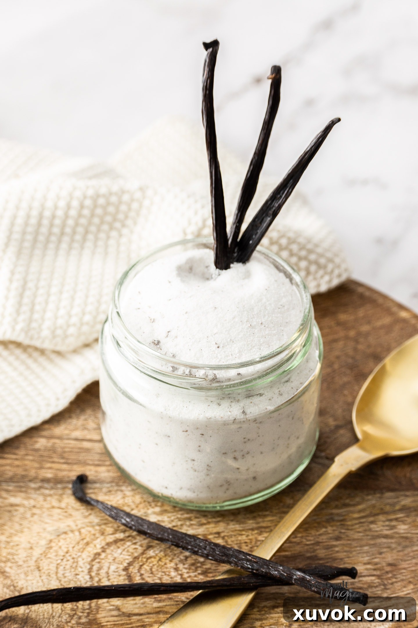 Three vanilla beans sticking out of a jar of vanilla sugar, highlighting the quality ingredients.