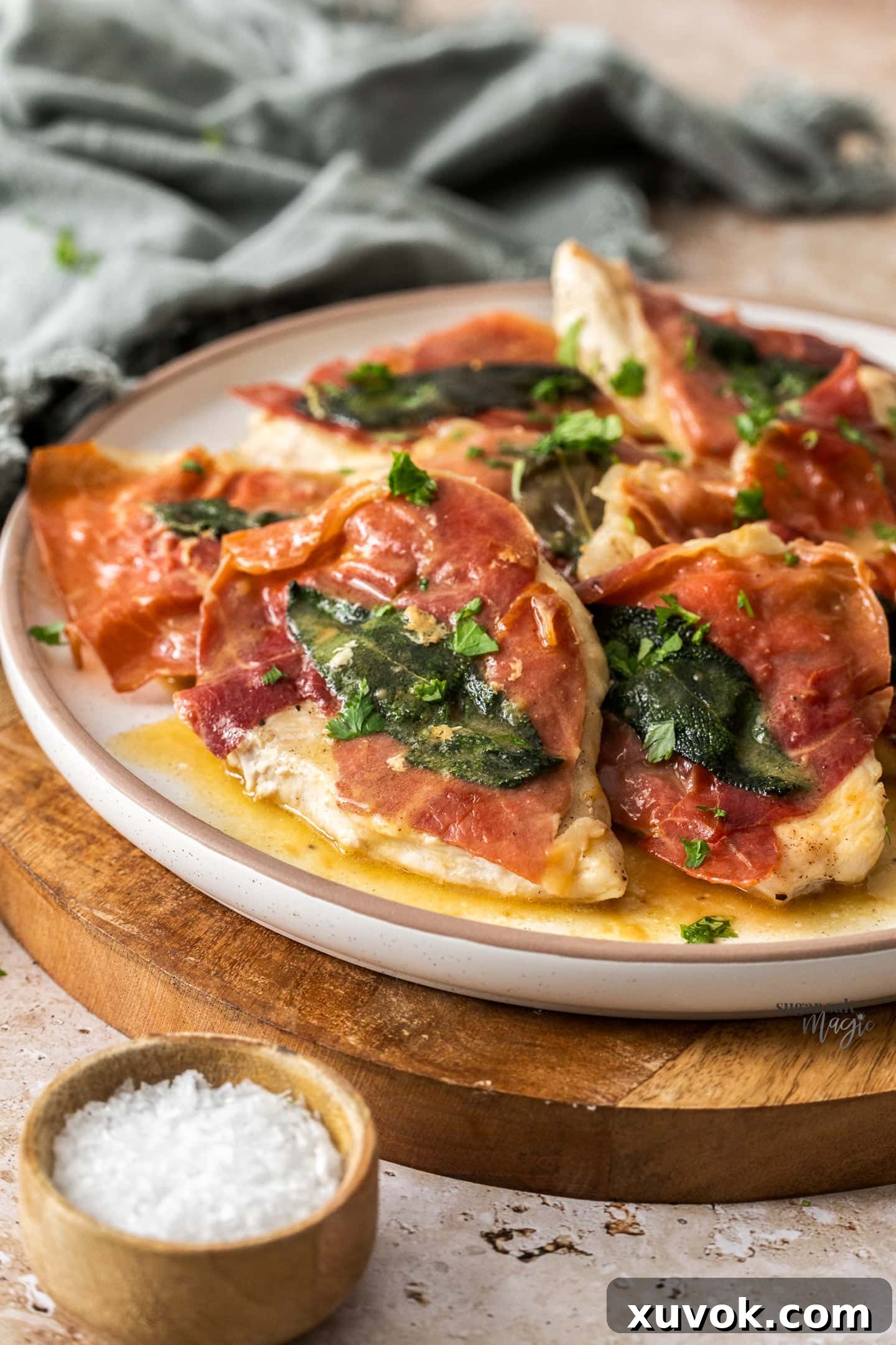 Slices of saltimbocca on a plate, garnished with fresh sage leaves.