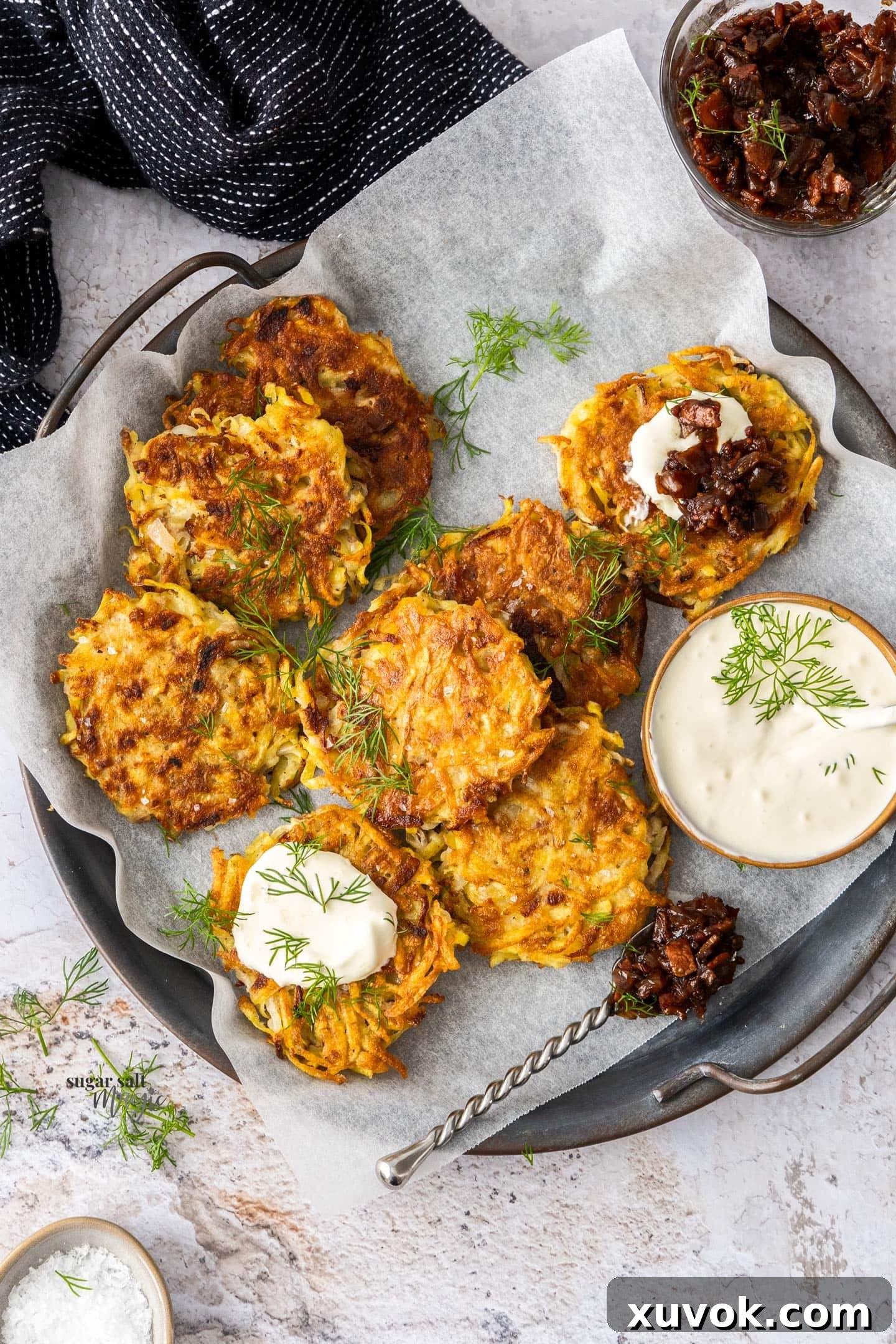 Eight golden, crispy potato fritters arranged artfully on a serving tray, garnished with fresh herbs.