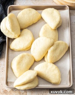 A batch of bao on top of a baking tray.