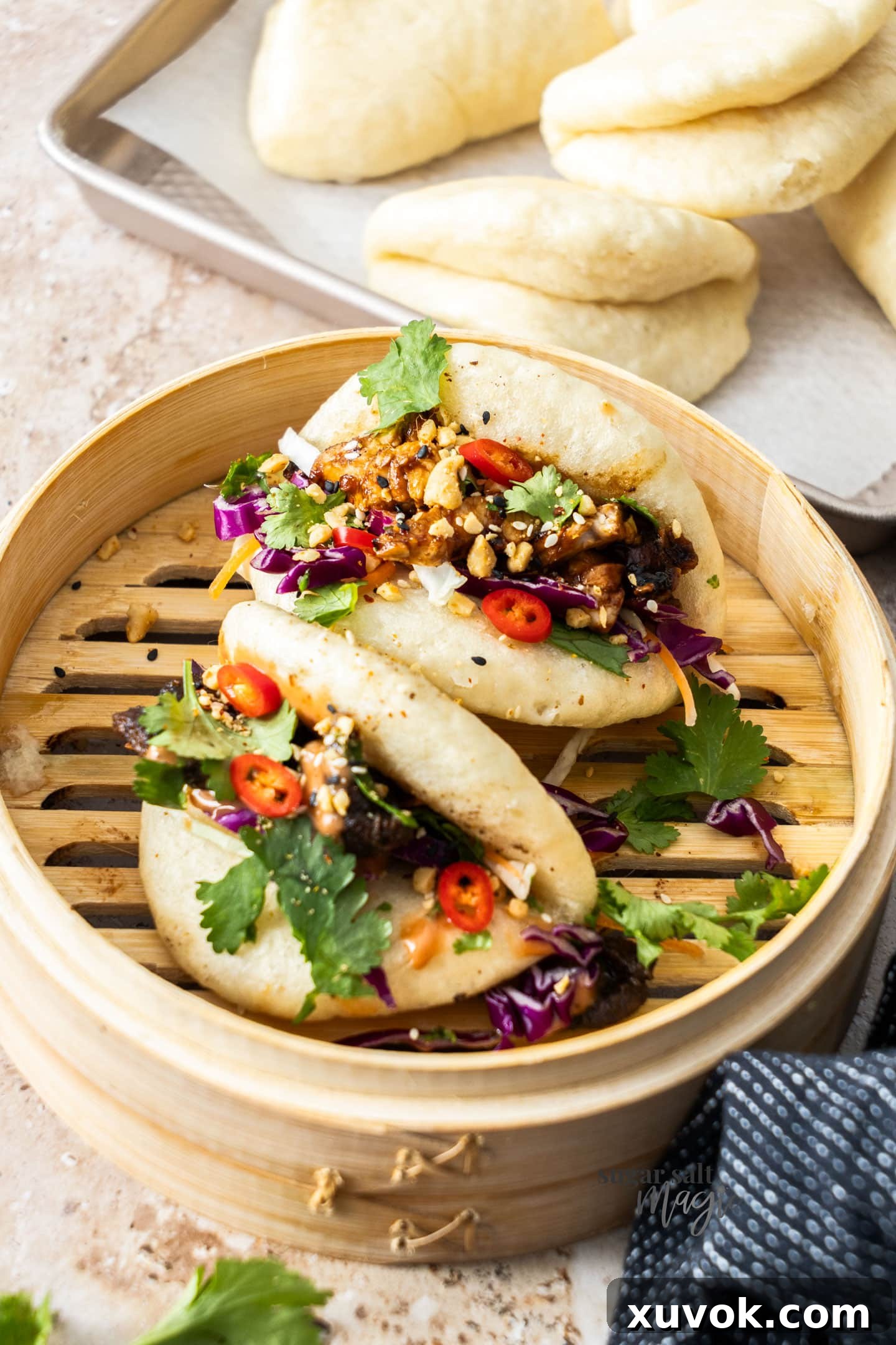 Two filled bao buns in a bamboo steamer.