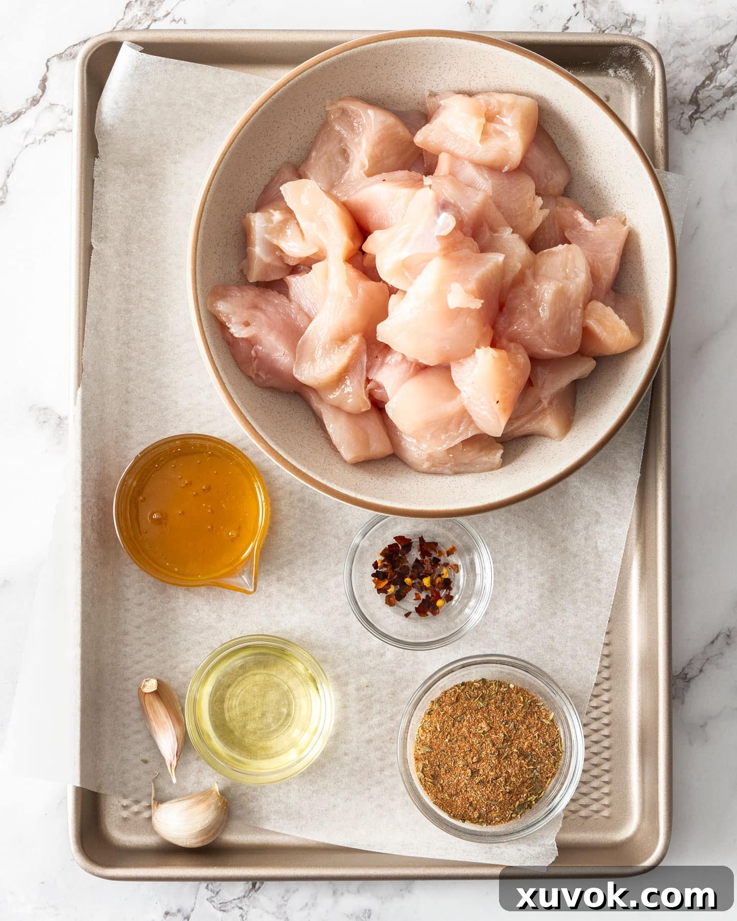 All the fresh ingredients laid out for making spicy chicken bites, including chicken, spices, honey, garlic, and fresh herbs.