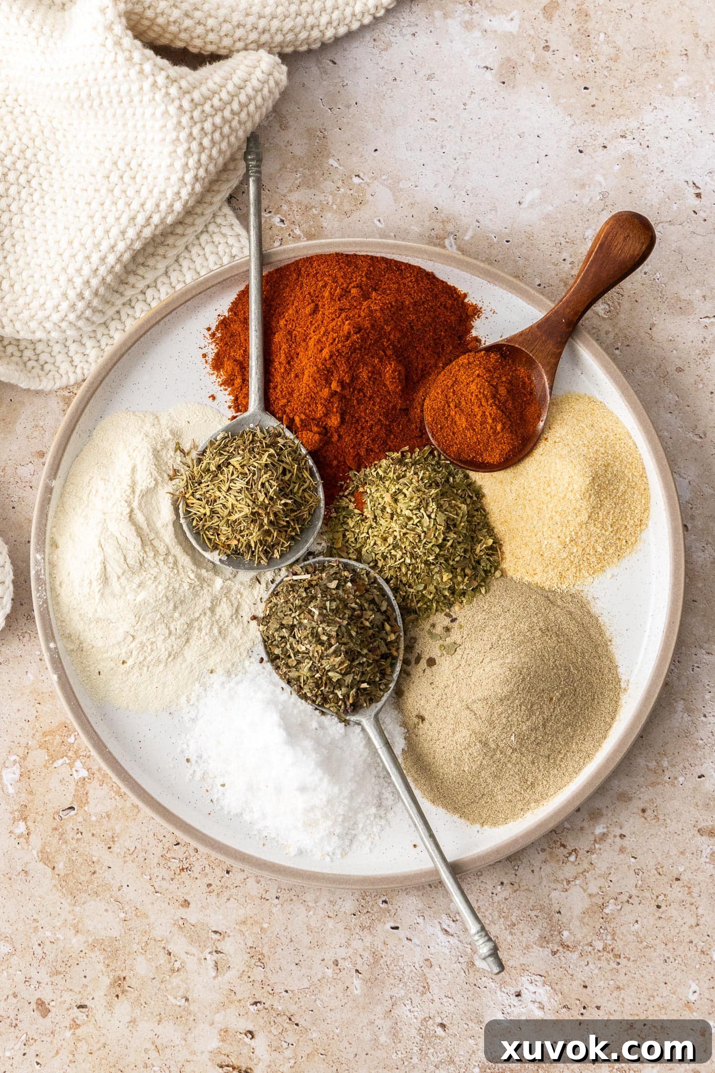 A collection of different vibrant spices and dried herbs arranged on a plate.