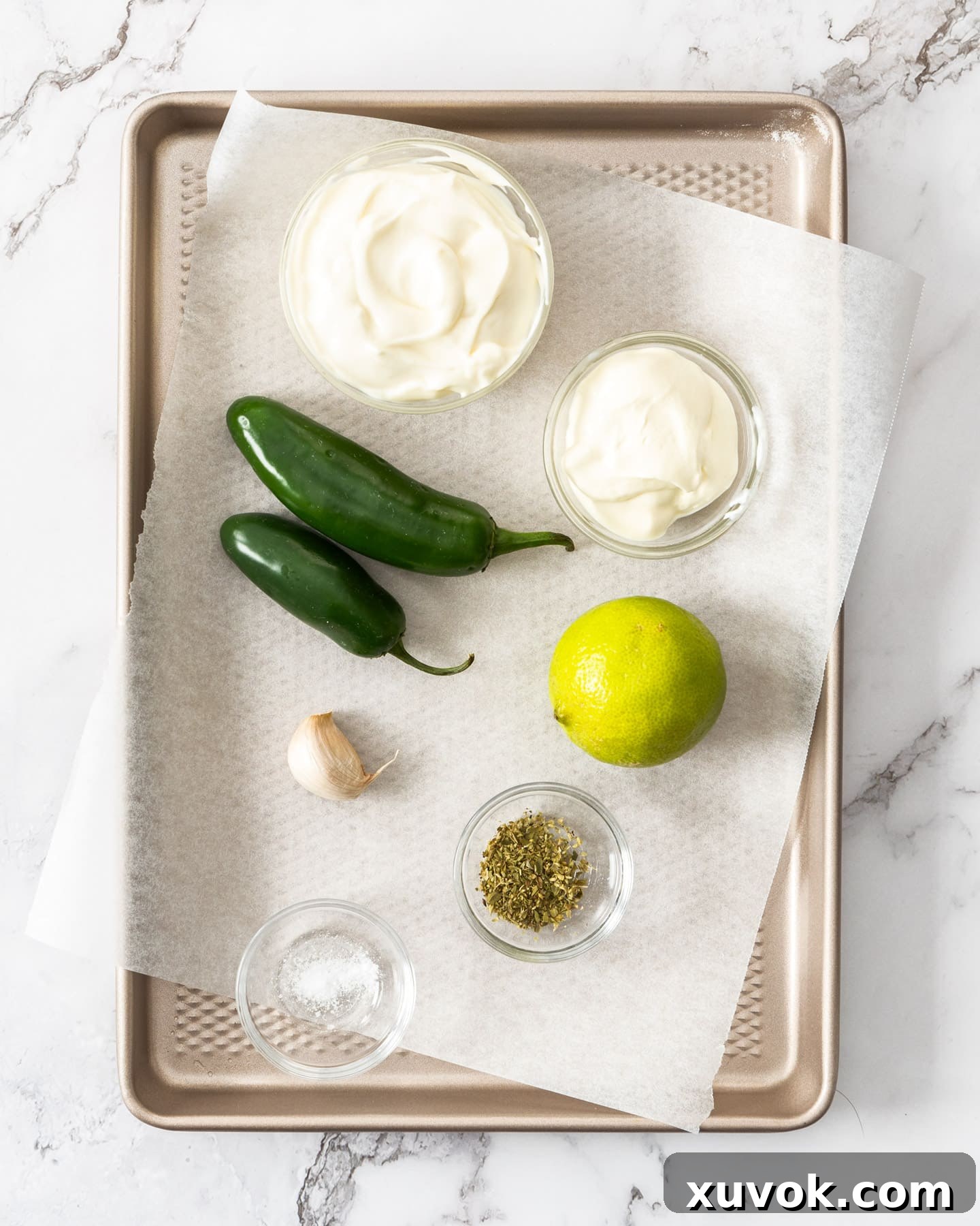 Ingredients for jalapeno mayo laid out on a baking tray, including mayonnaise, sour cream, jalapenos, garlic, lime, and oregano.