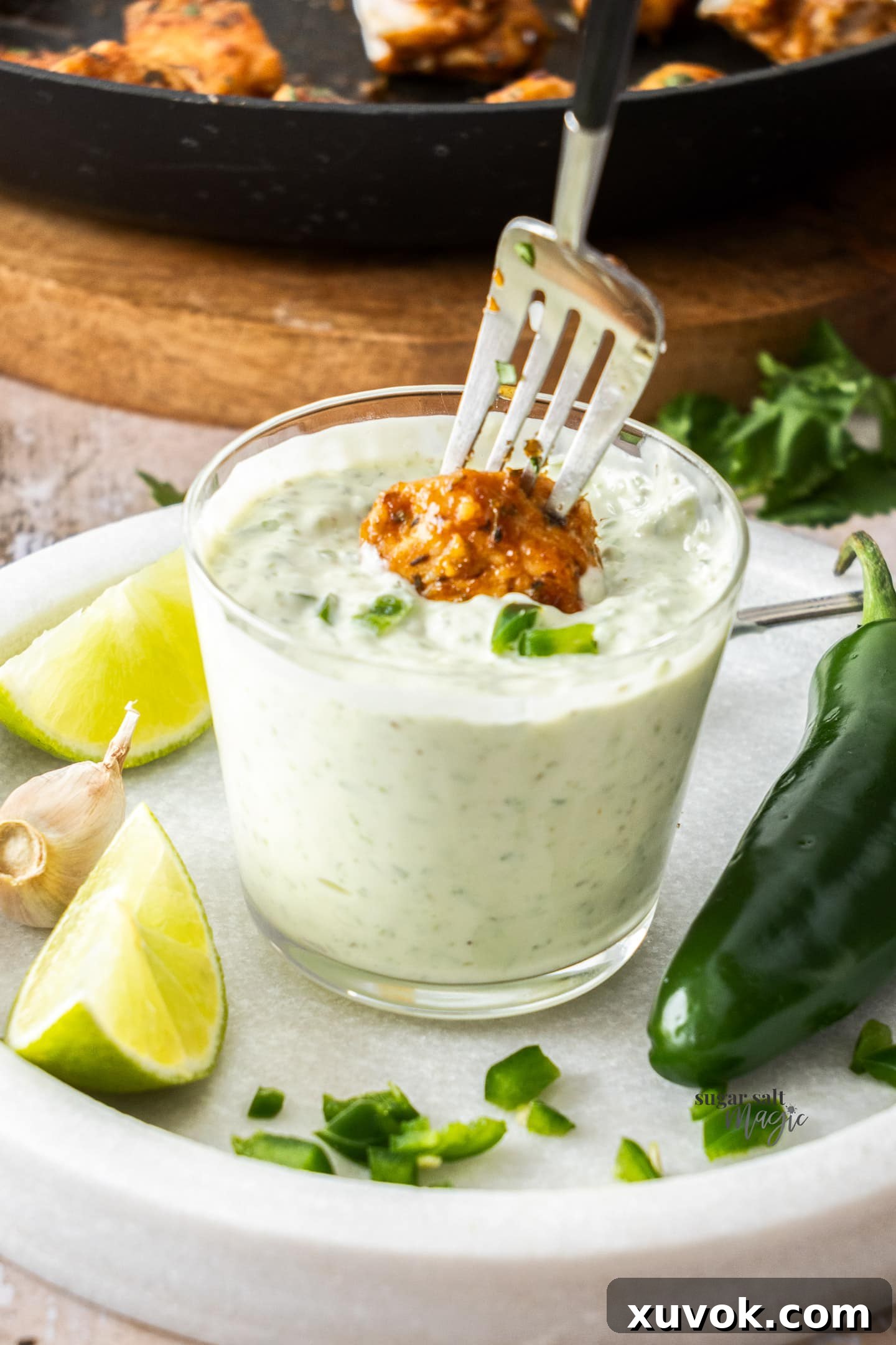 A piece of crispy chicken being dipped into a bowl of creamy jalapeno mayo.