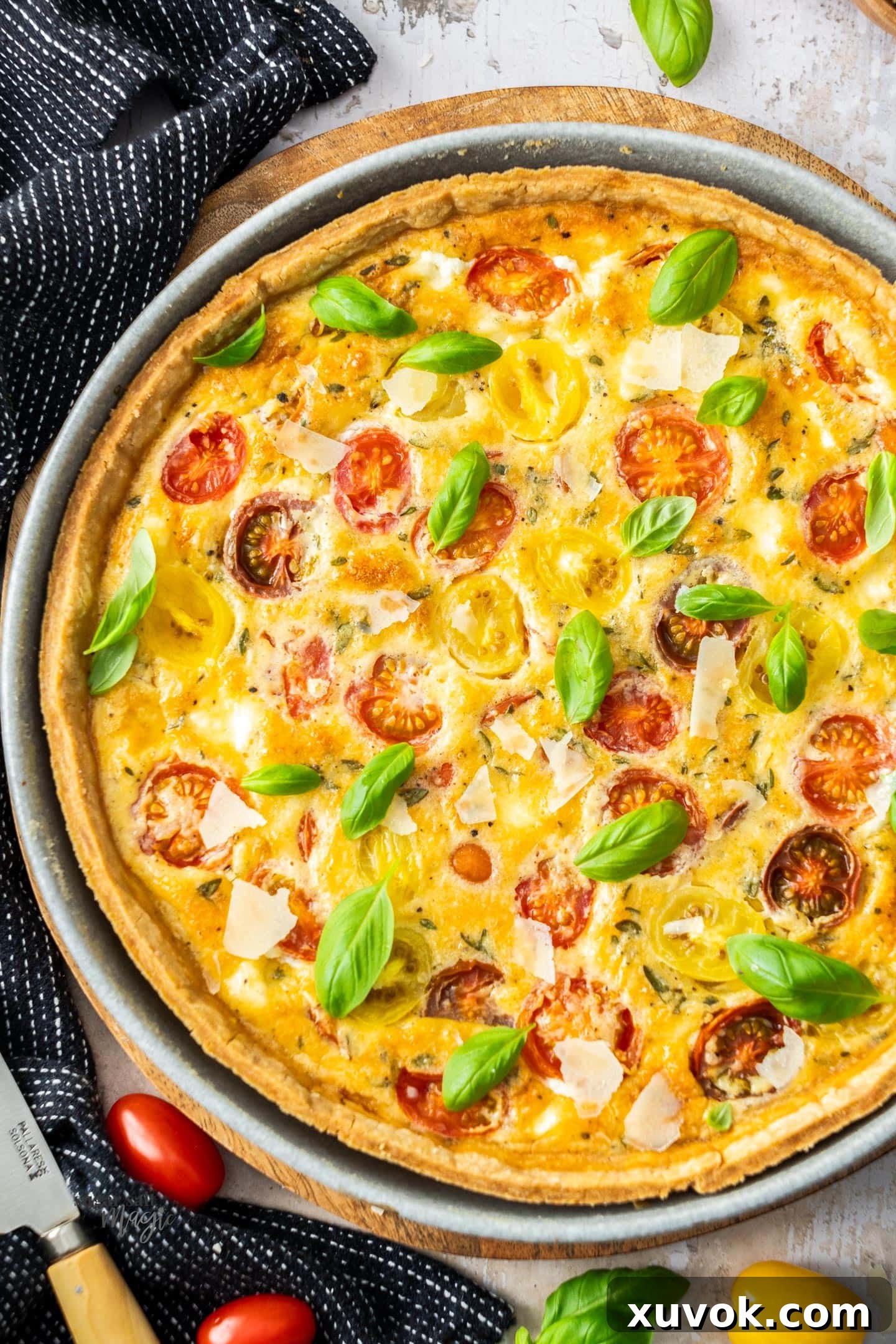 Top down view of a quiche in a dish filled with tomatoes.