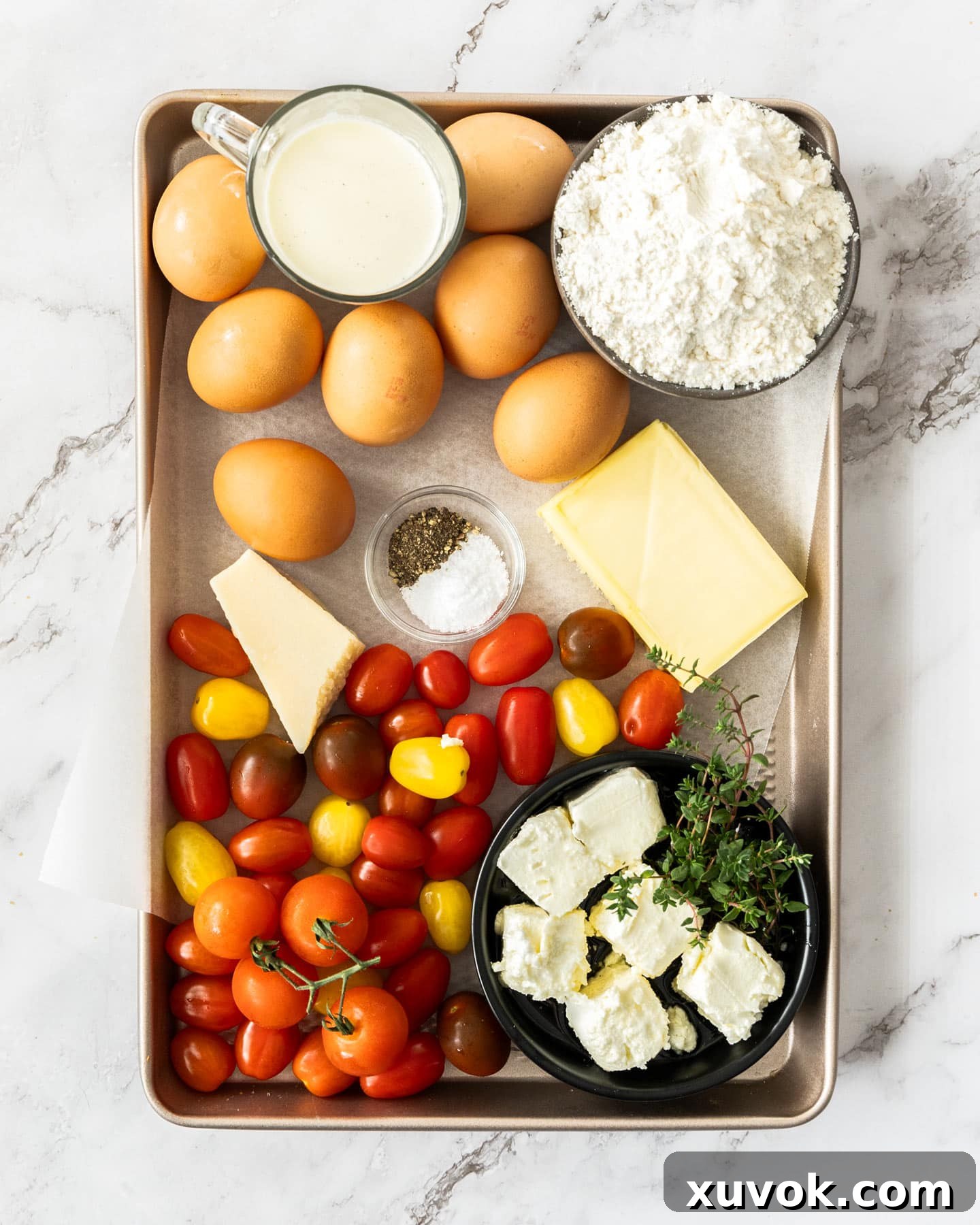 Ingredients for cheese and tomato quiche on a baking tray.