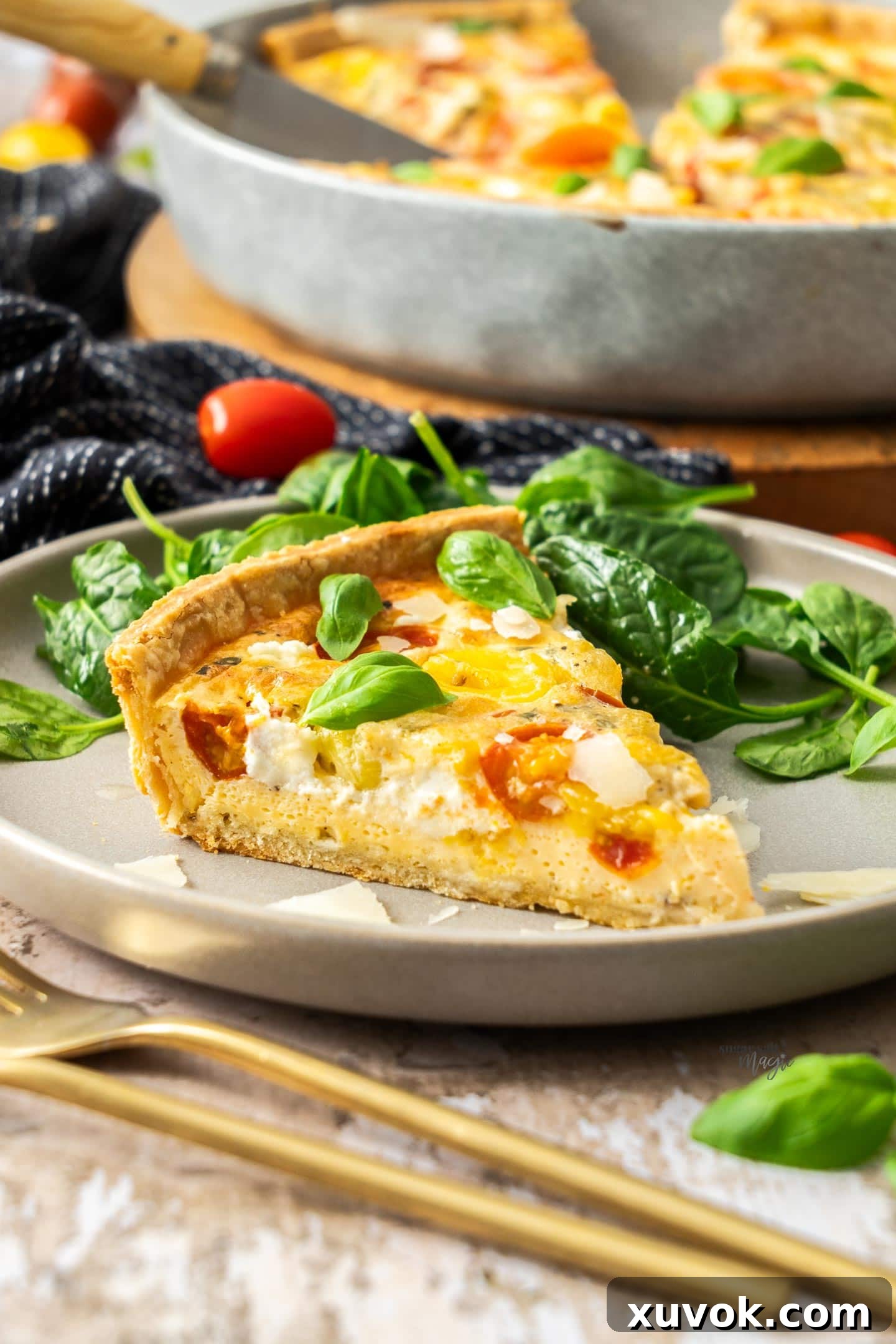 A slice of cheese and tomato quiche on a plate.