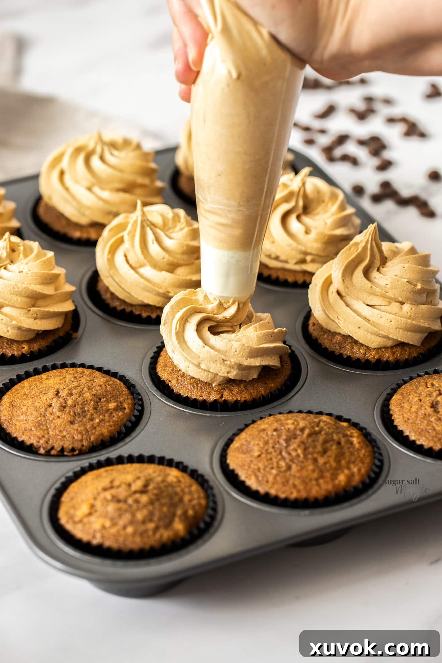 Coffee buttercream being piped onto a cupcake.