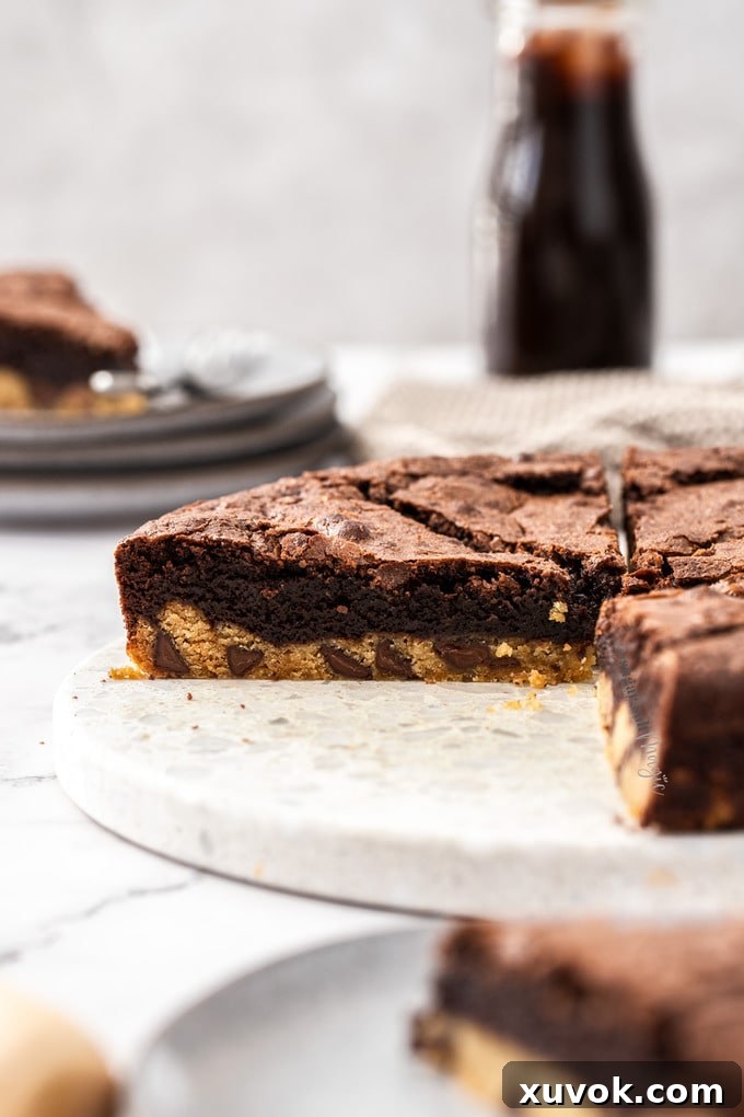 A slice of brookie pie on a white stone platter with another slice in the foreground.