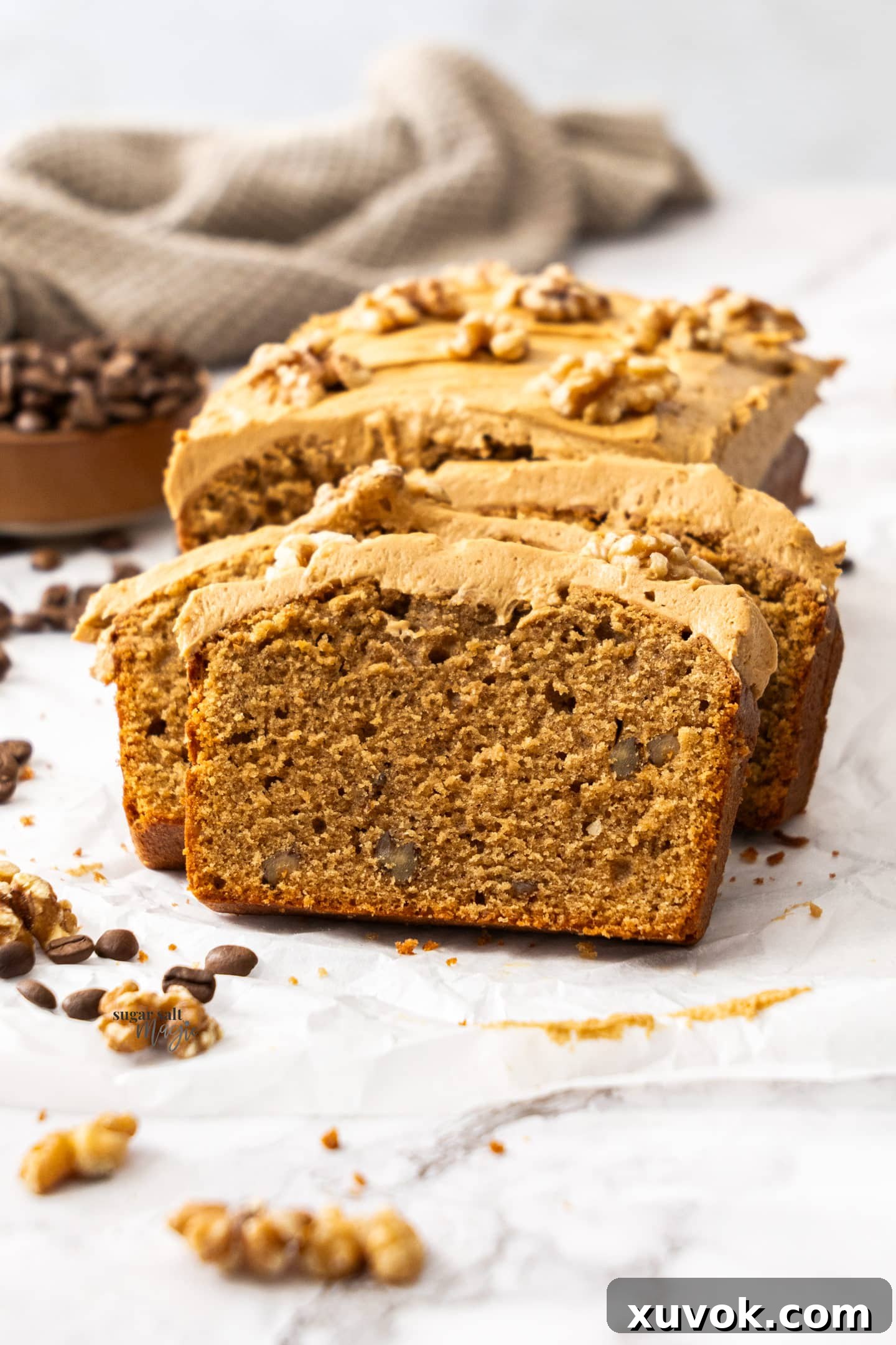 Stacked slices of moist coffee and walnut loaf cake, showcasing its tender crumb and creamy coffee frosting, ready to be enjoyed as a delightful tea time treat.