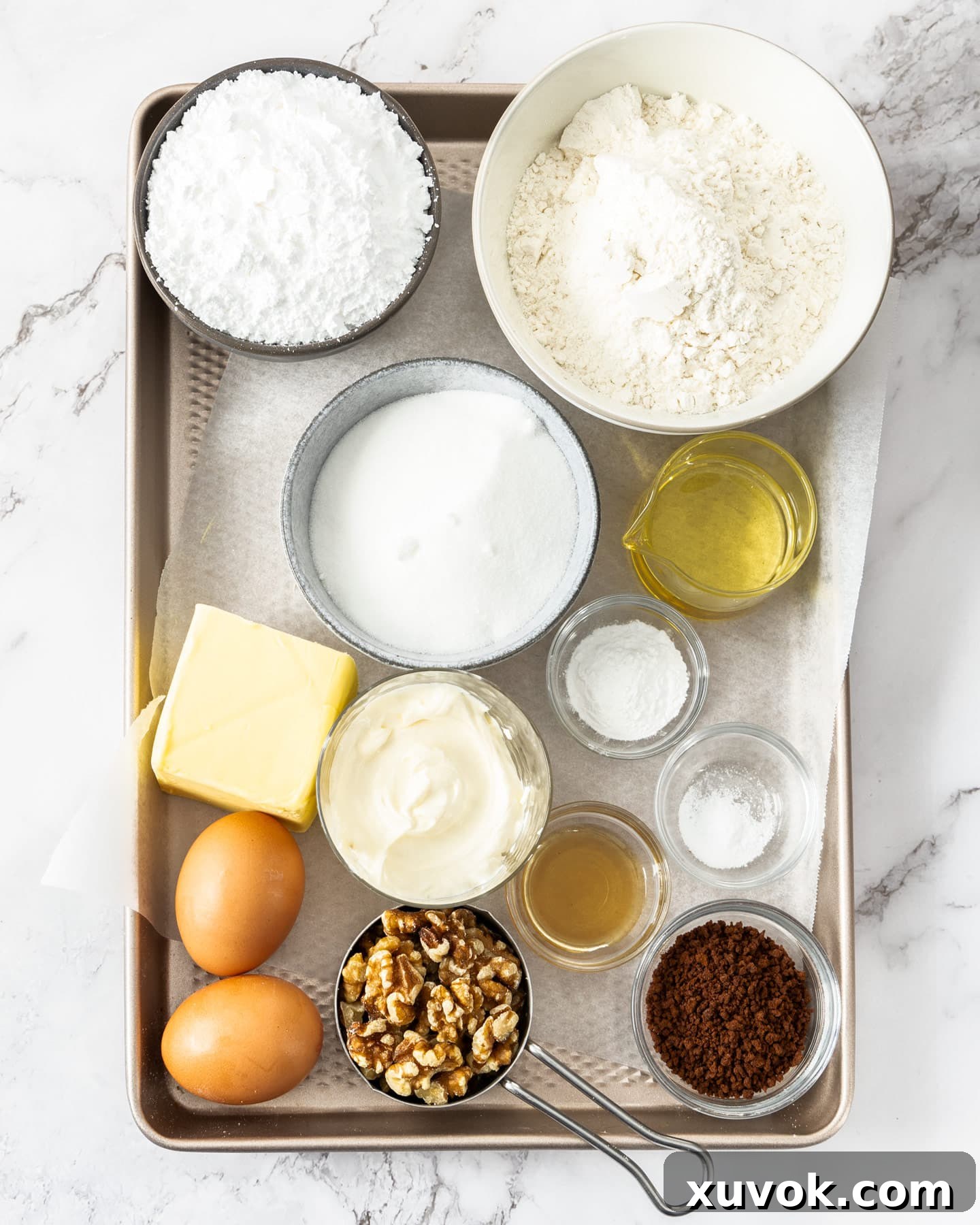A curated collection of fresh ingredients for baking coffee walnut loaf, including flour, sugar, butter, eggs, sour cream, coffee, and walnuts, arranged neatly on a baking tray.