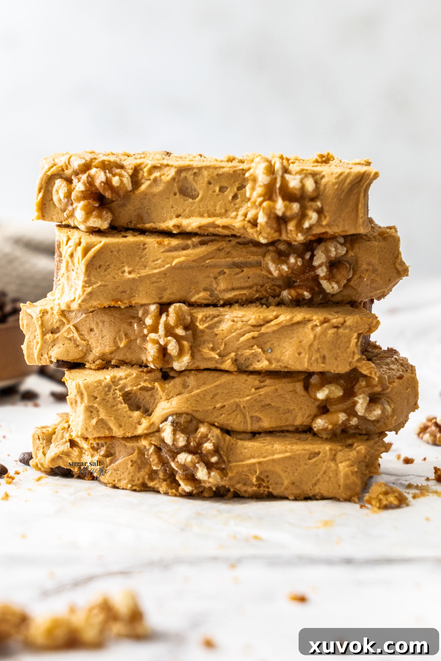 A delightful stack of five moist slices of coffee and walnut loaf cake, each topped with creamy coffee buttercream, ready for a delicious indulgence.