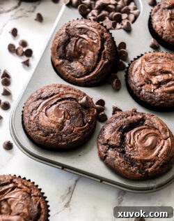 Six perfectly baked triple chocolate muffins with a sprinkling of chocolate chips, arranged artfully for a mouth-watering presentation.